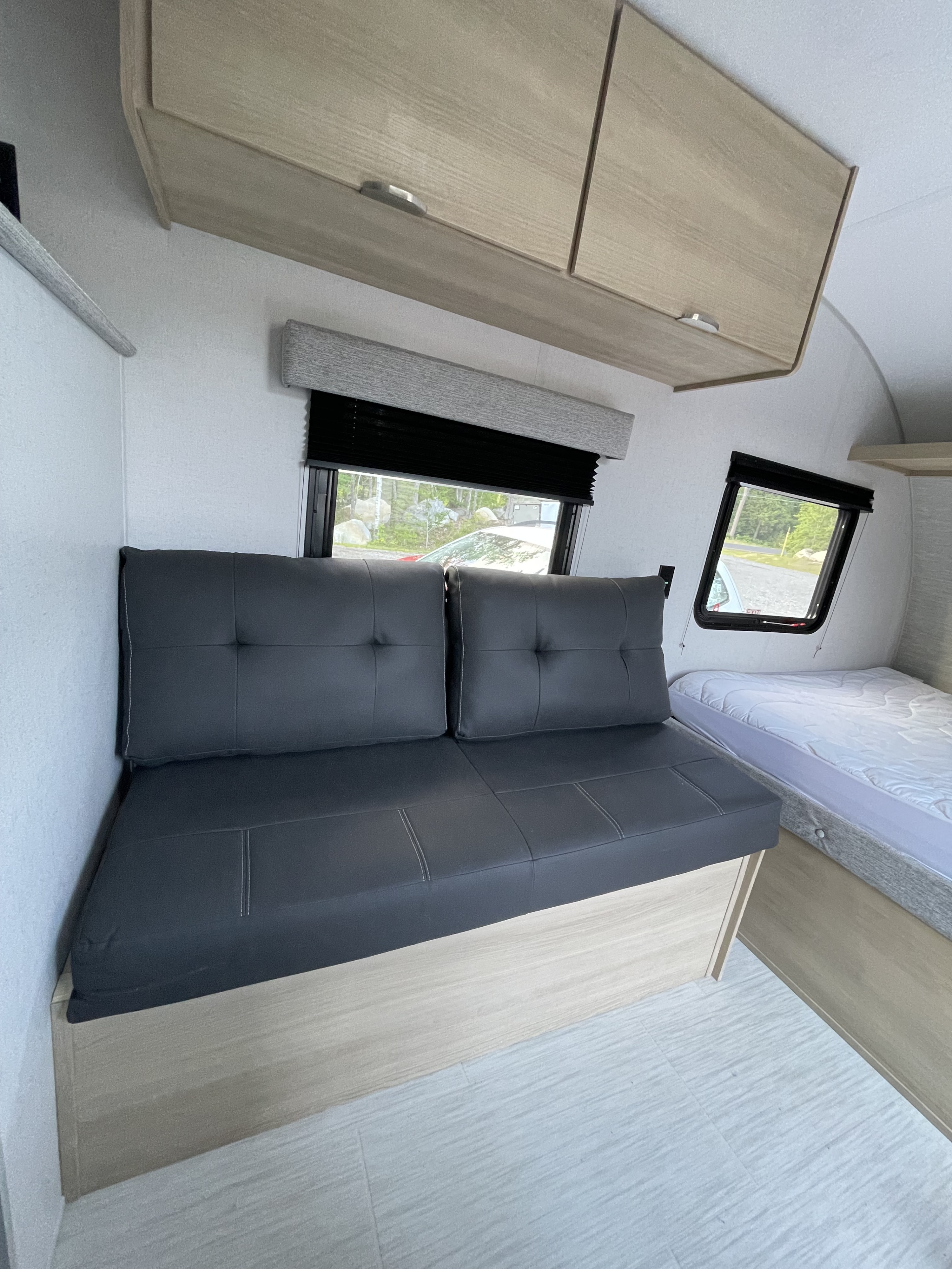 RV rental interior with a black futon sofa, light wood cabinets, and a bed. Bright and modern camper space.. Forest River Salem 2024
