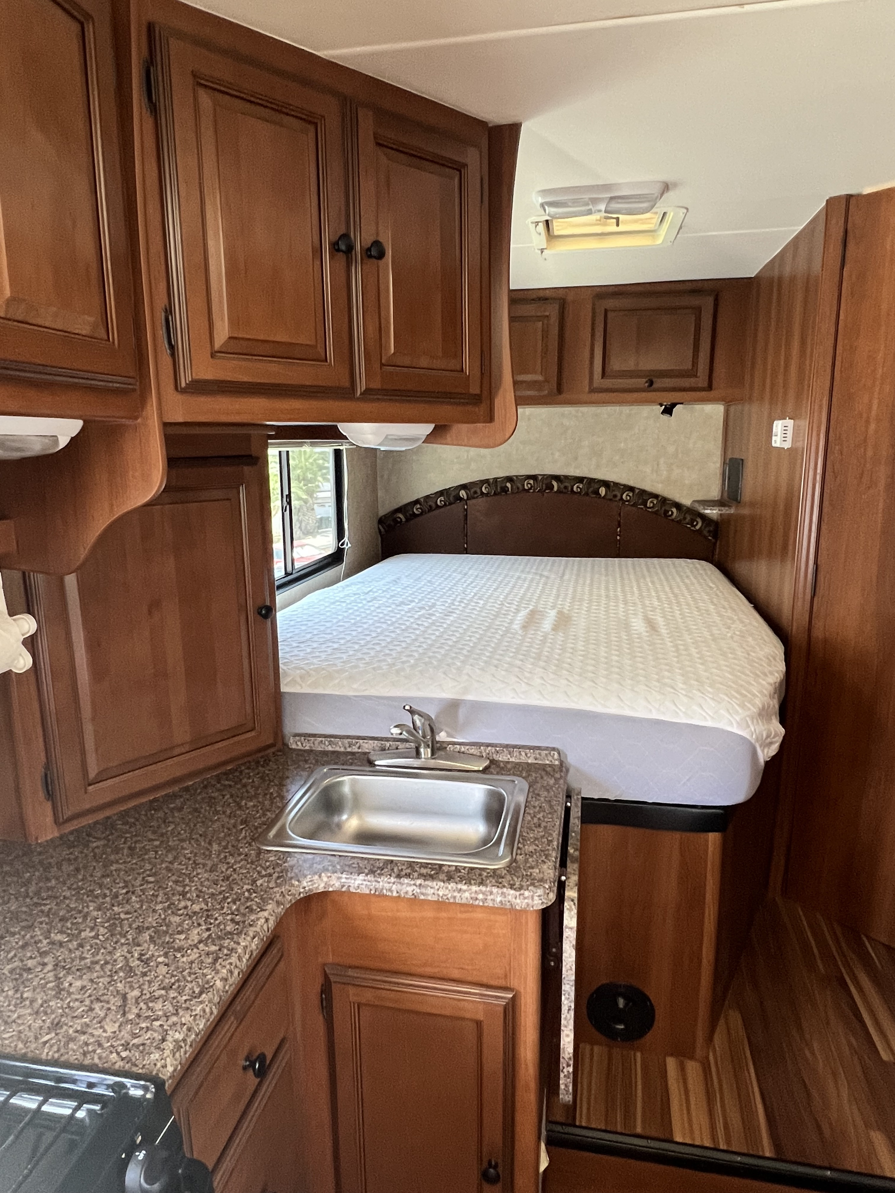 Cozy RV rental interior: wood cabinets, kitchen with sink, and comfy bed create a welcoming space.. Coachmen Leprechaun 2014