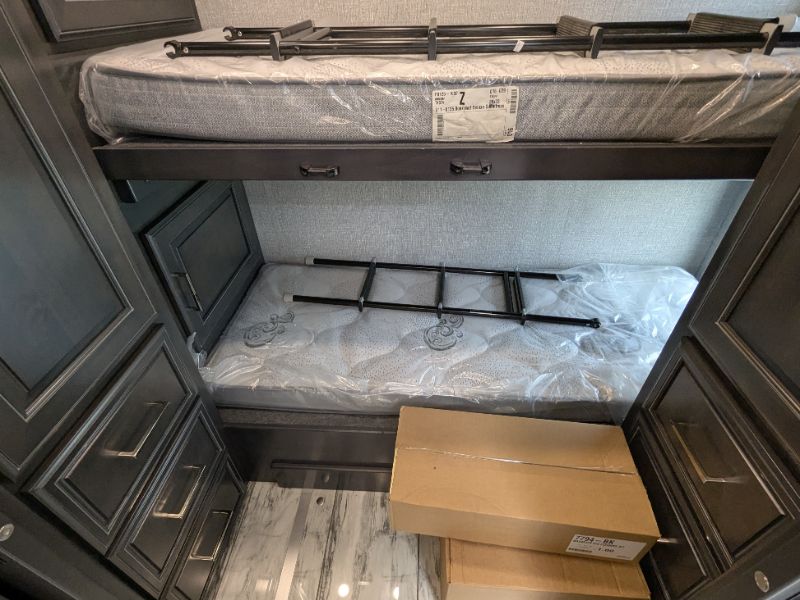 RV rental interior with new, plastic-covered bunk beds & built-in storage, ready for your trip.. Fleetwood Discovery 2025