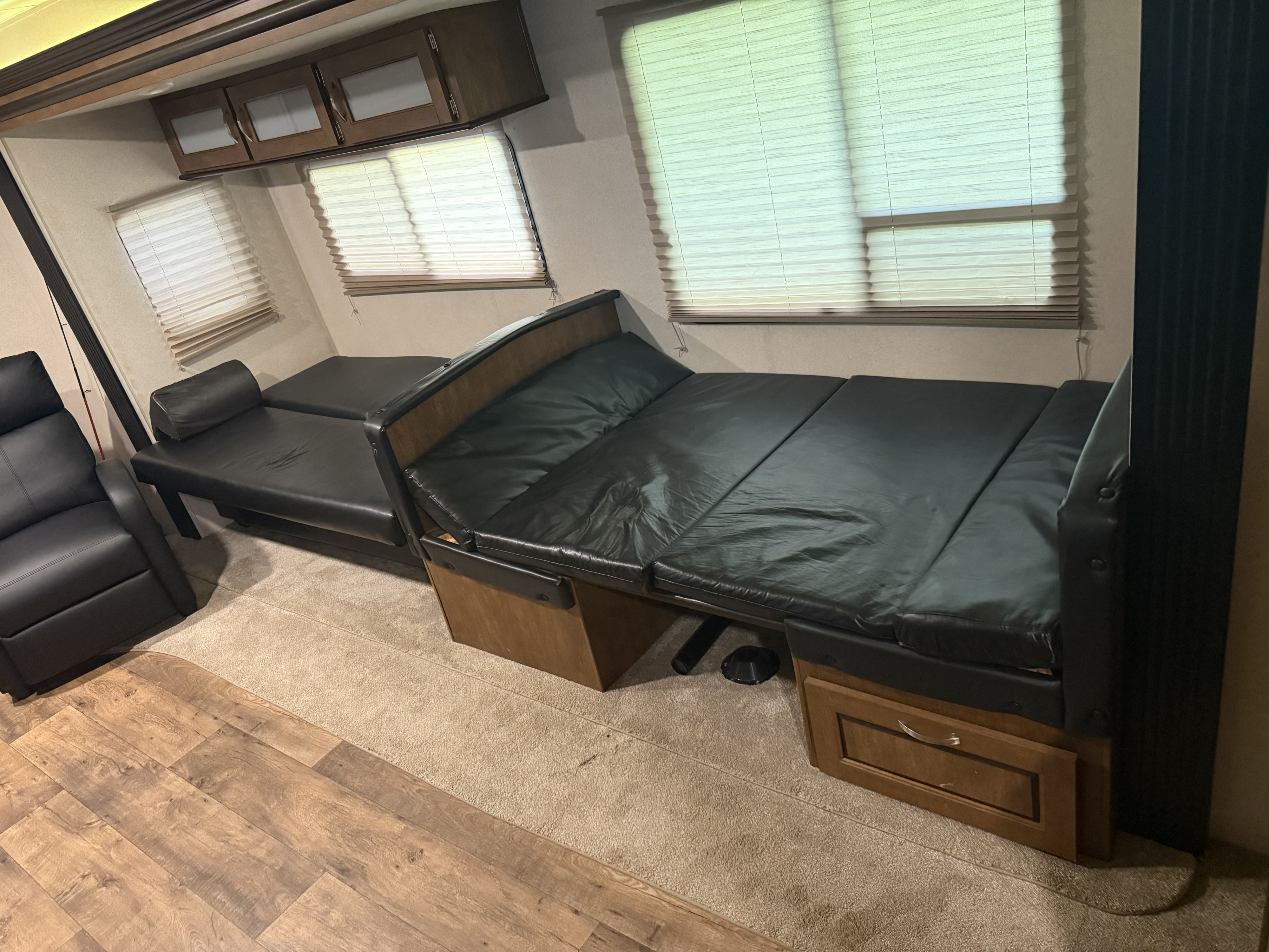 Spacious RV rental interior: black leather recliner, extended sofa-bed, overhead cabinets, and mixed flooring.. Forest River Salem 2017