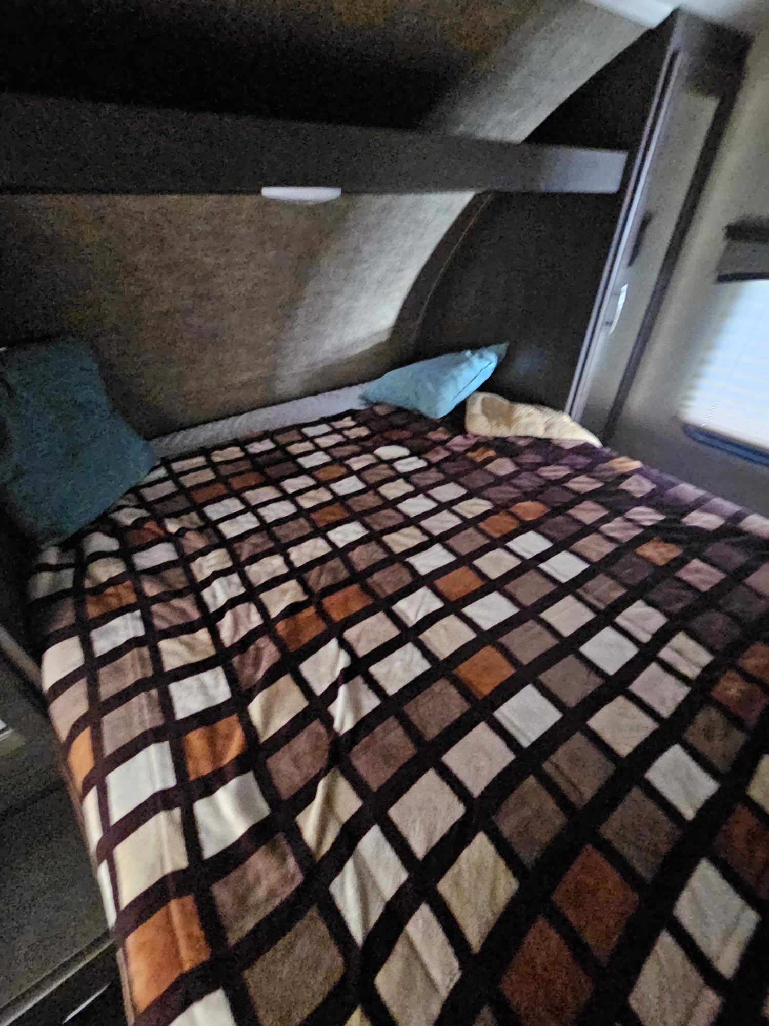 Cozy RV rental bedroom featuring a bed with a brown and white patterned blanket and pillows, for comfortable travel.. Forest River Sierra 2017