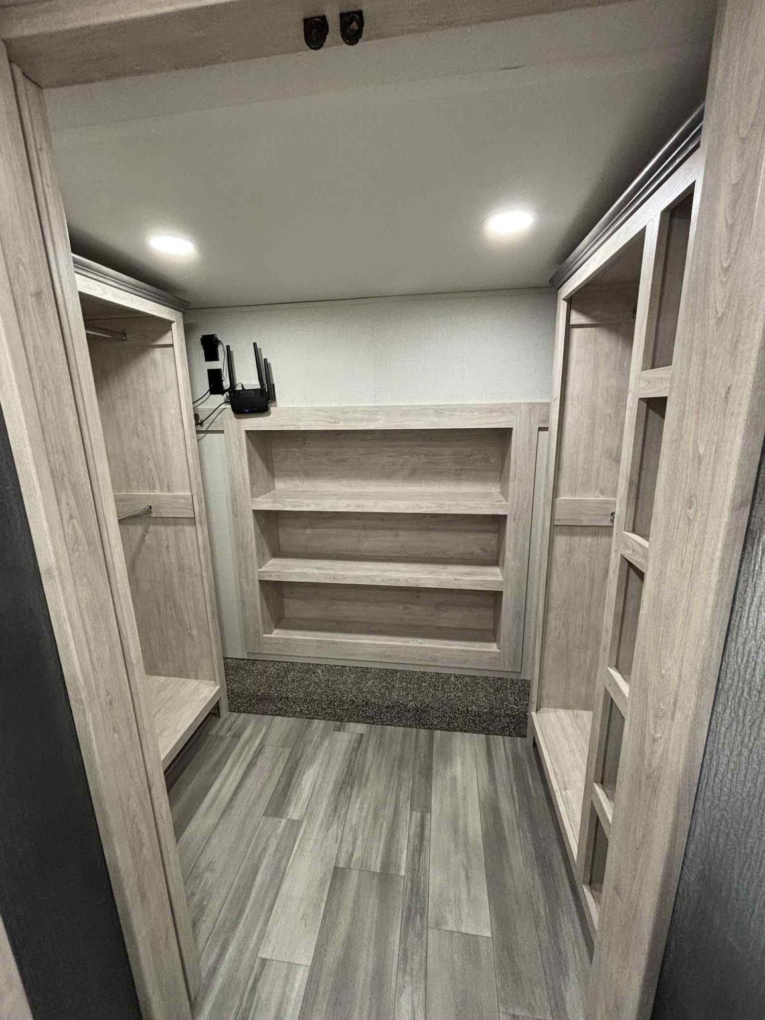 Spacious RV rental interior: a bright, built-in closet and storage with shelves, hanging rods, and a media setup for convenience.. Forest River Sandpiper 2024