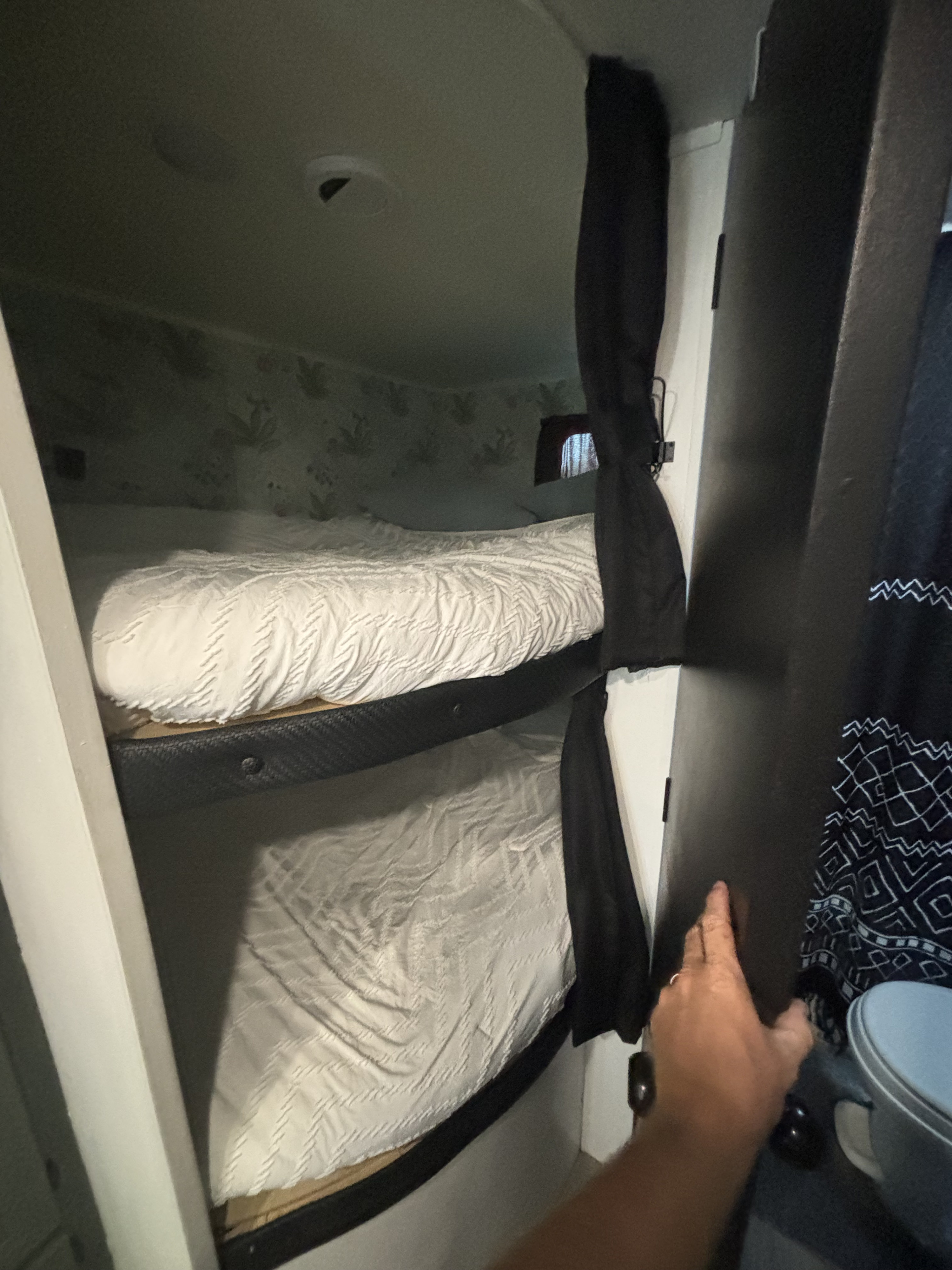 Inside an RV rental, two bunk beds with clean white bedding offer a cozy sleeping area. View of compact interior space.. Jayco Jay Flight 2022