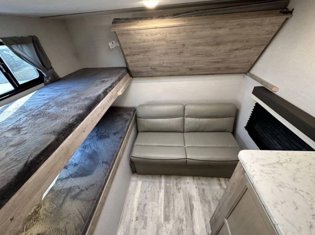 Inside an RV rental: bunk beds, comfy sofa, and an overhead fold-down bed maximize space for travelers.. Gulf Stream Trailmaster 2023