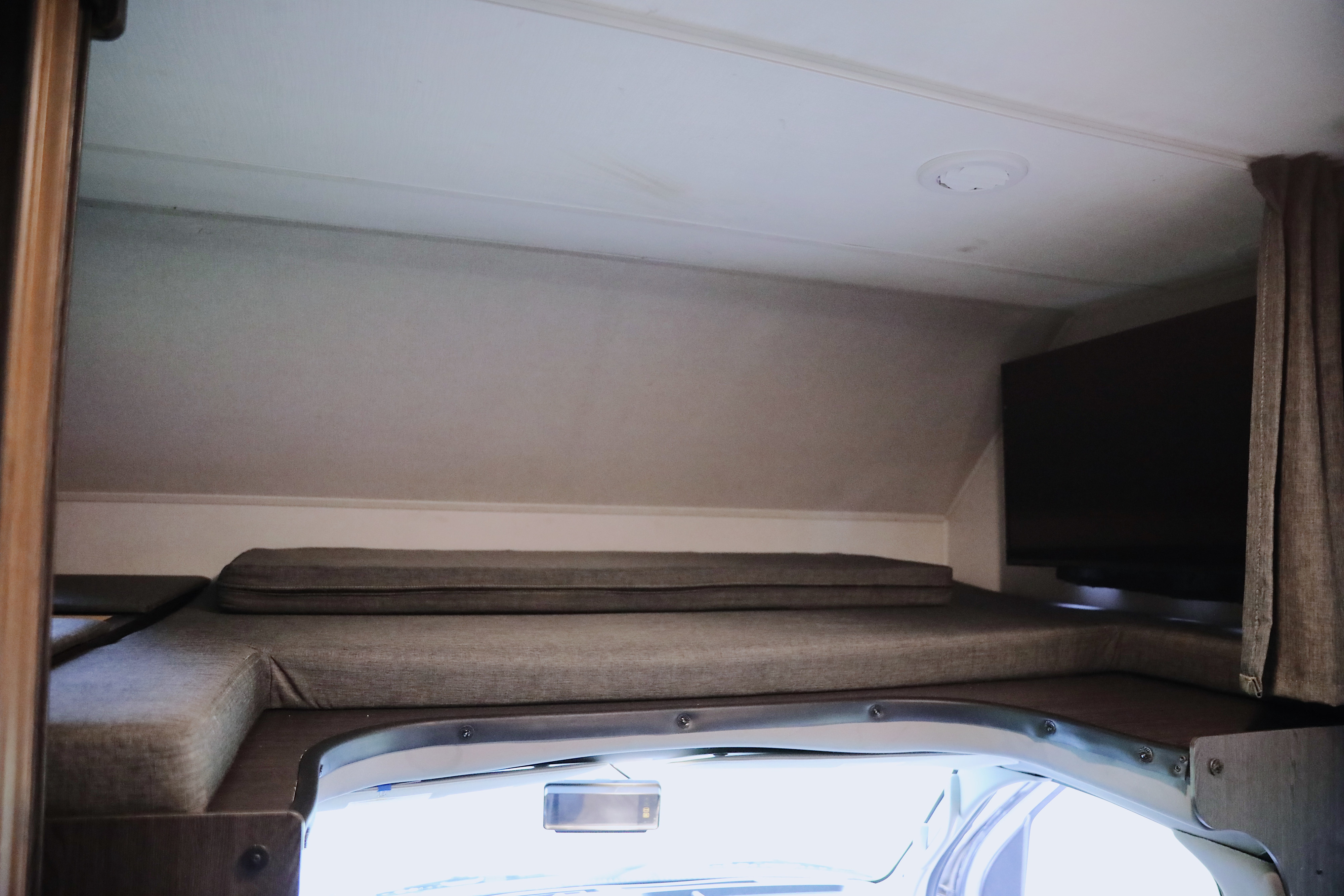 RV rental: Cozy overhead sleeping area with cushions, a mounted TV, and front windshield view in this camper.. Forest River Sunseeker LE 2022
