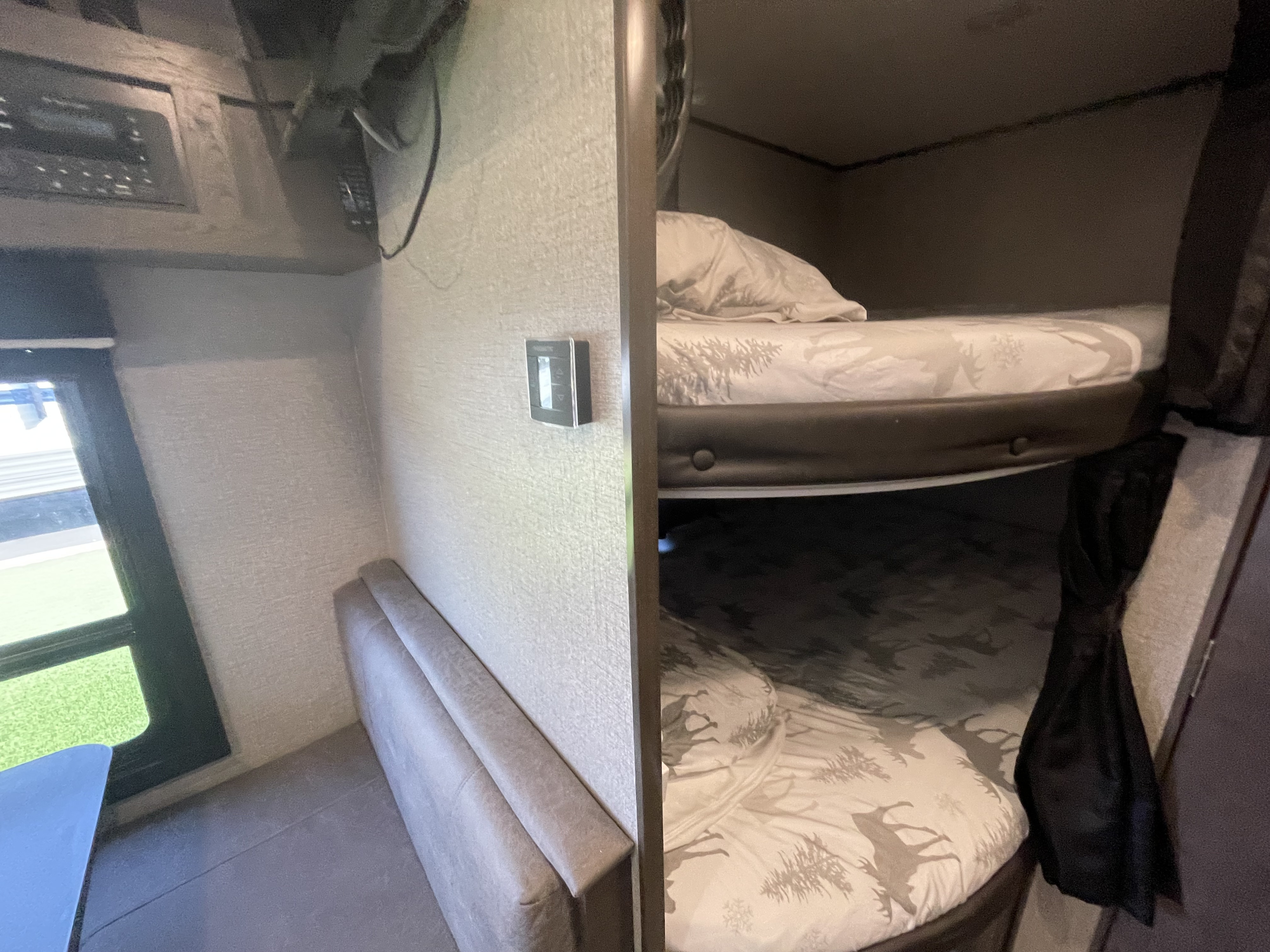 Cozy RV rental interior: stacked bunk beds with themed bedding, a dinette with a window, and control panel.. Jayco Jay Flight SLX Rocky Mountain Edition 2021