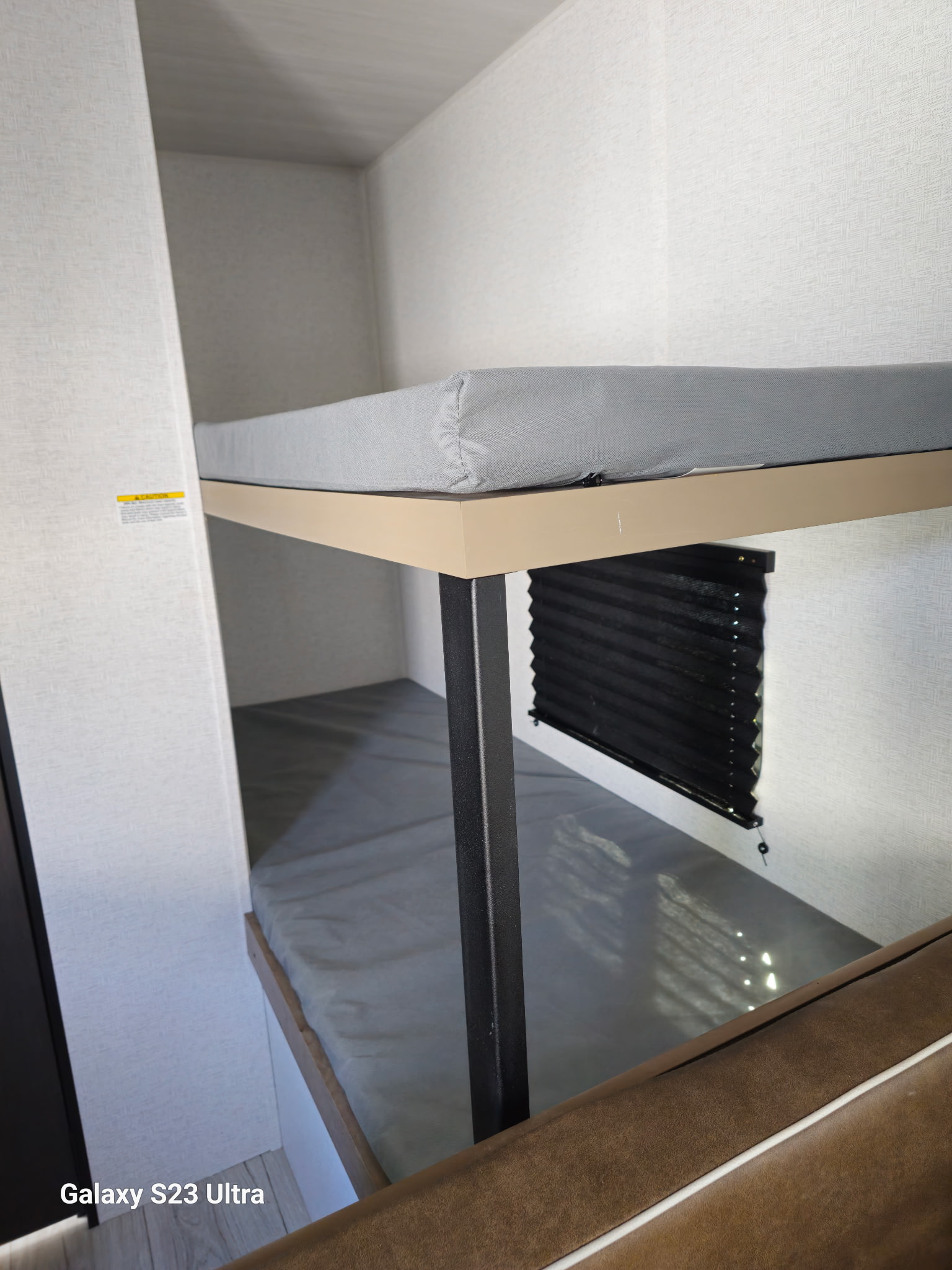 RV rental bunk beds with grey mattresses and a window blind. Perfect sleeping area for an RV interior.. Keystone RV Springdale 2025