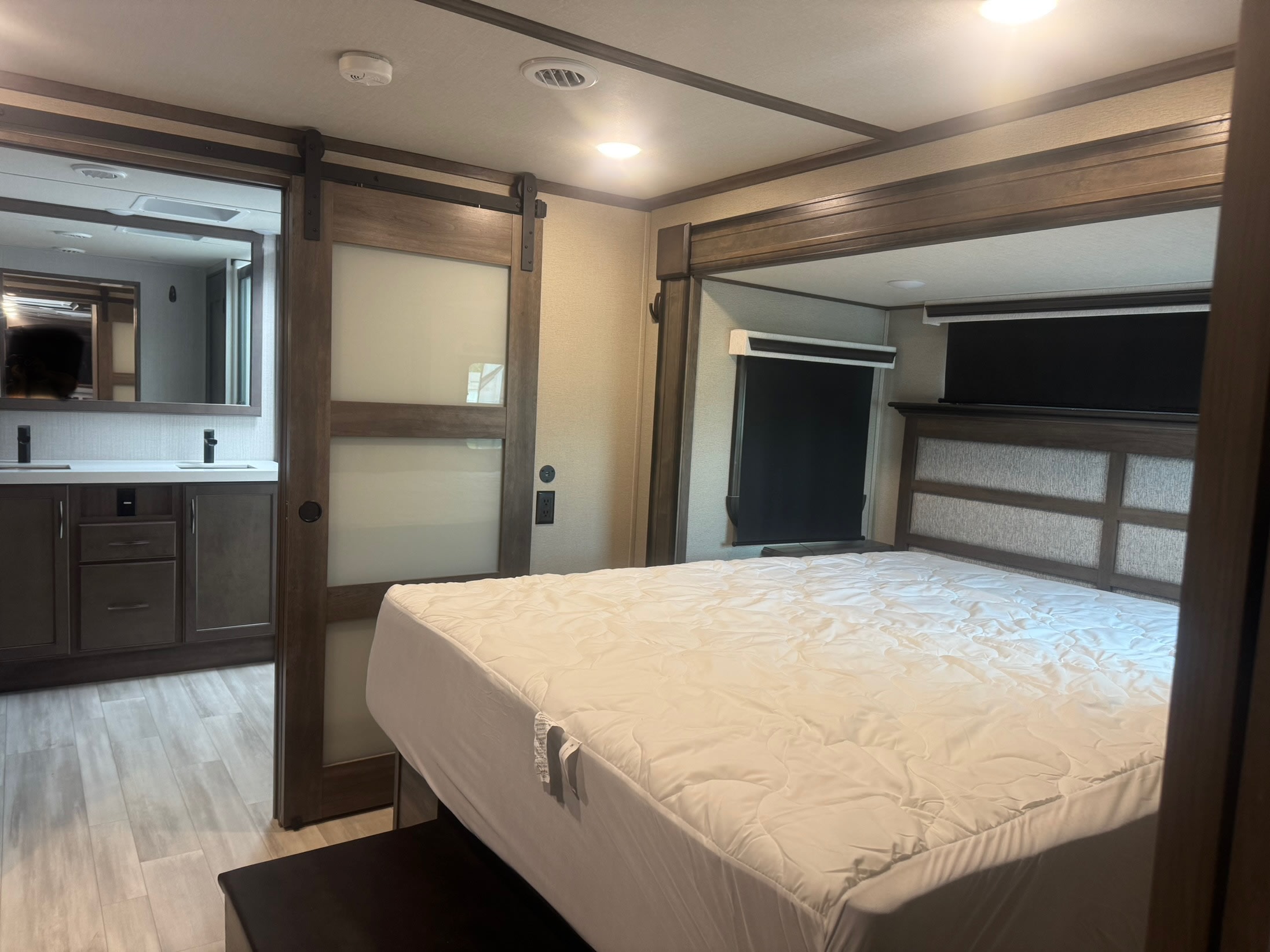 Spacious RV rental bedroom with connected double vanity bathroom, featuring modern design and sliding barn doors.. Grand Design Solitude 2022