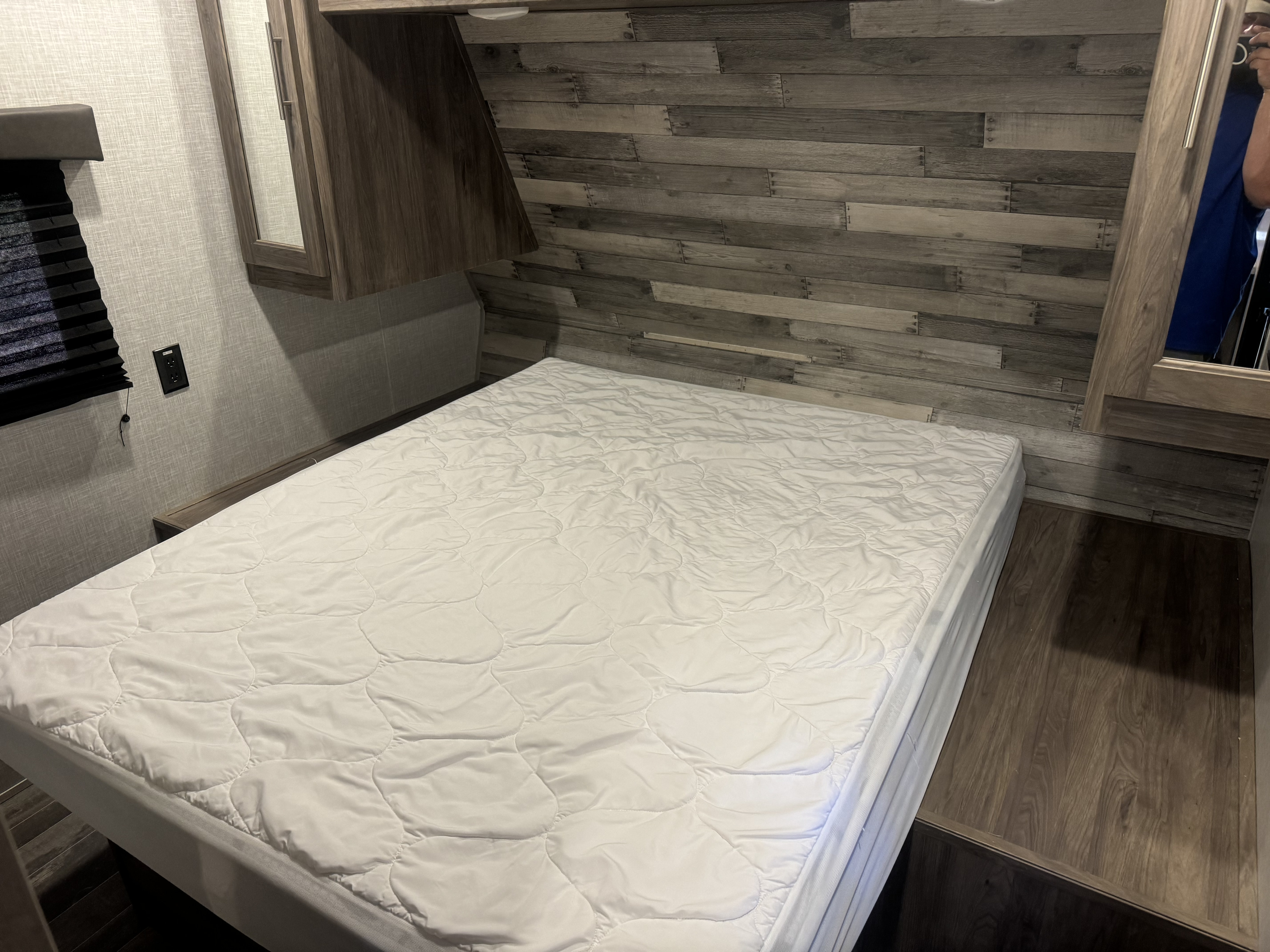 Inside this RV rental: A compact bedroom with a comfortable bed, quilted mattress pad, mirrored cabinets, and window.. Keystone Zinger 290KB 2022