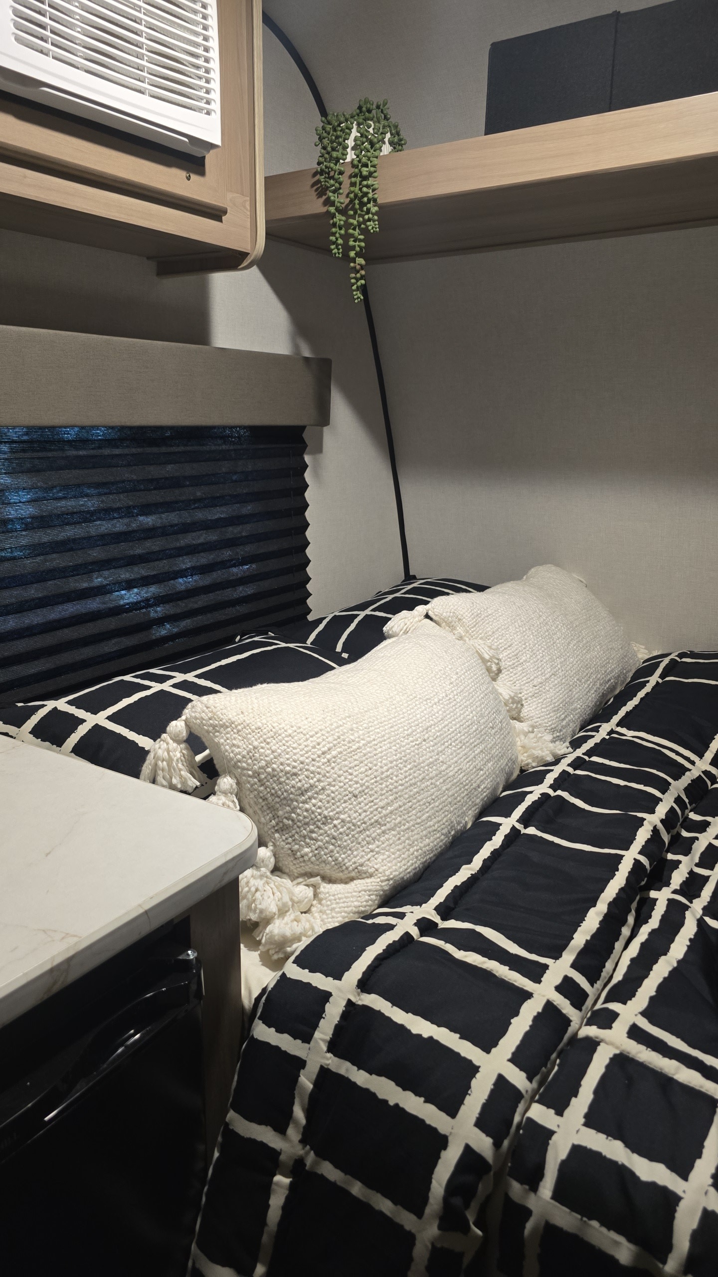 Cozy RV rental interior: A bed with black & white bedding, white pillows, window blinds, and overhead AC unit.. Keystone RV Coleman 13B 2025