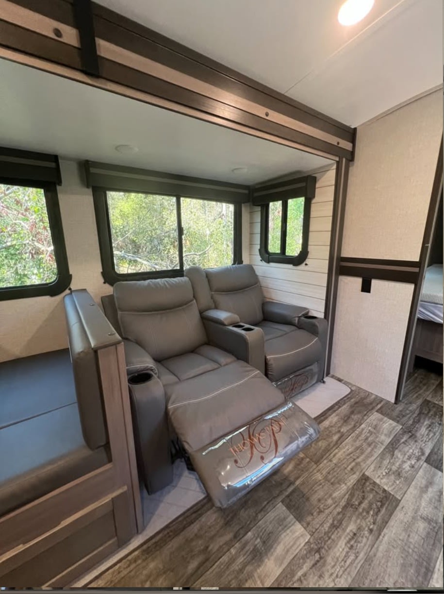 Spacious RV rental living area featuring comfortable grey recliners with extended footrests, large windows, and a versatile bench/bed.. Crossroads RV Sunset Trail Super Lite 2022