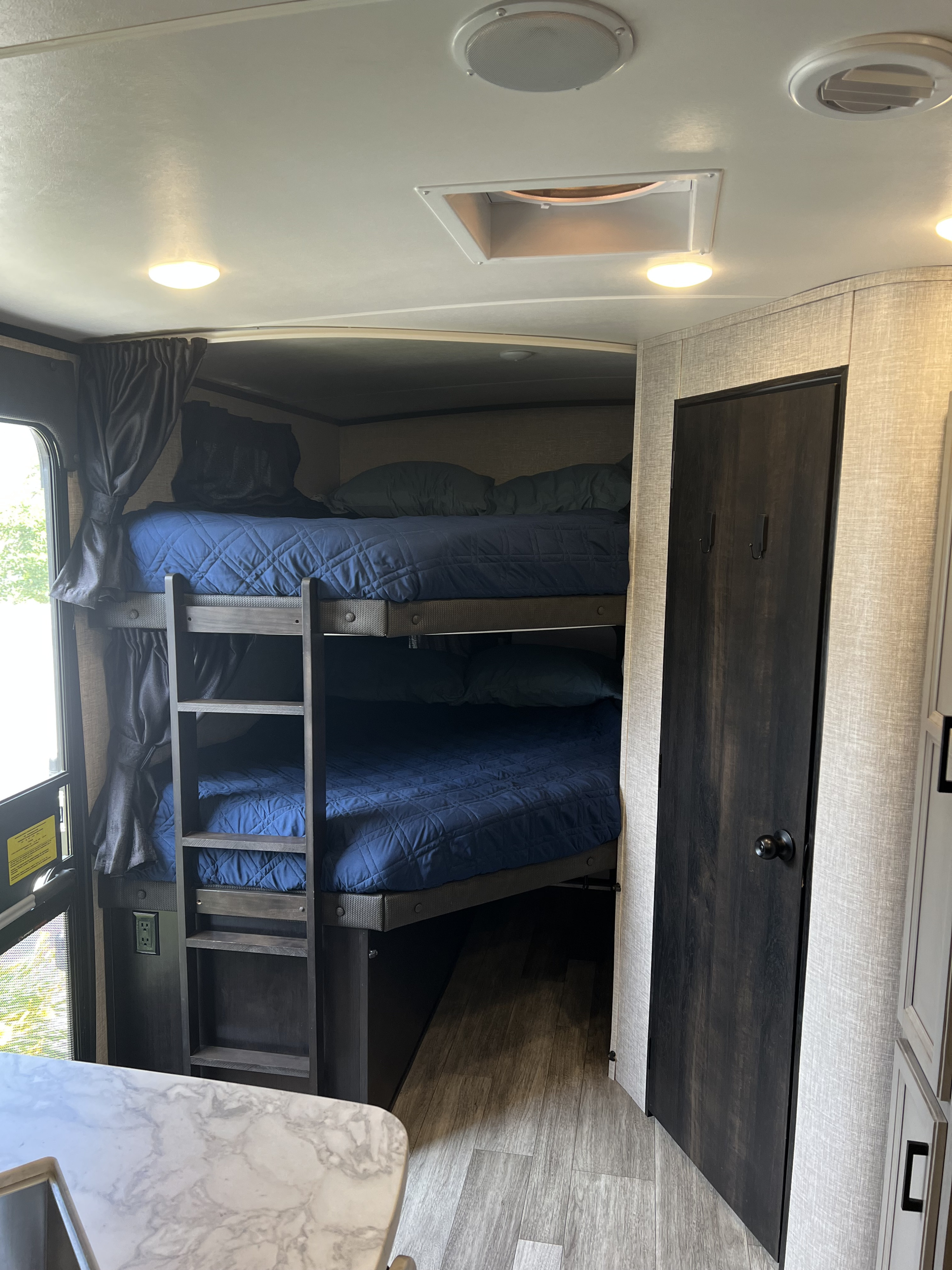 RV rental: Interior shot showing cozy bunk beds with blue bedding, a ladder for access, and a dark wood door.. Jayco White Hawk 2022