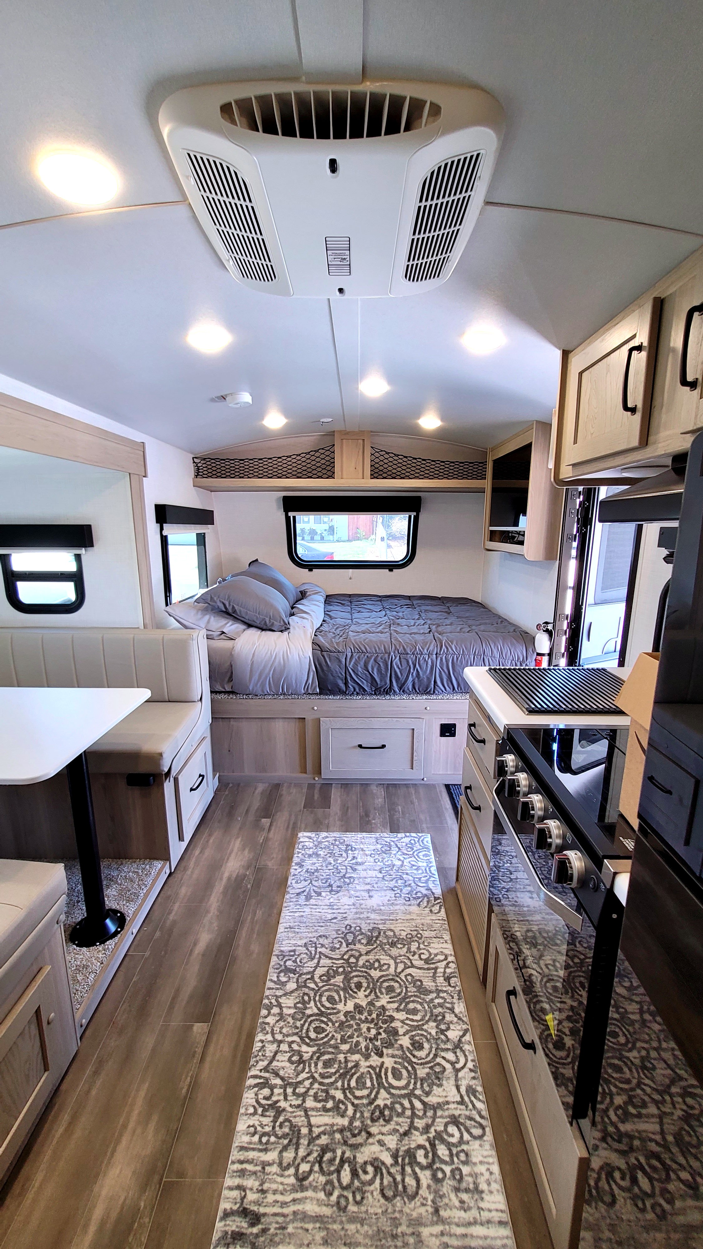 Inside a cozy **RV rental**: bed, dinette, and kitchen area visible. Perfect for travel and compact living.. Forest River Rockwood Geo Pro 2024