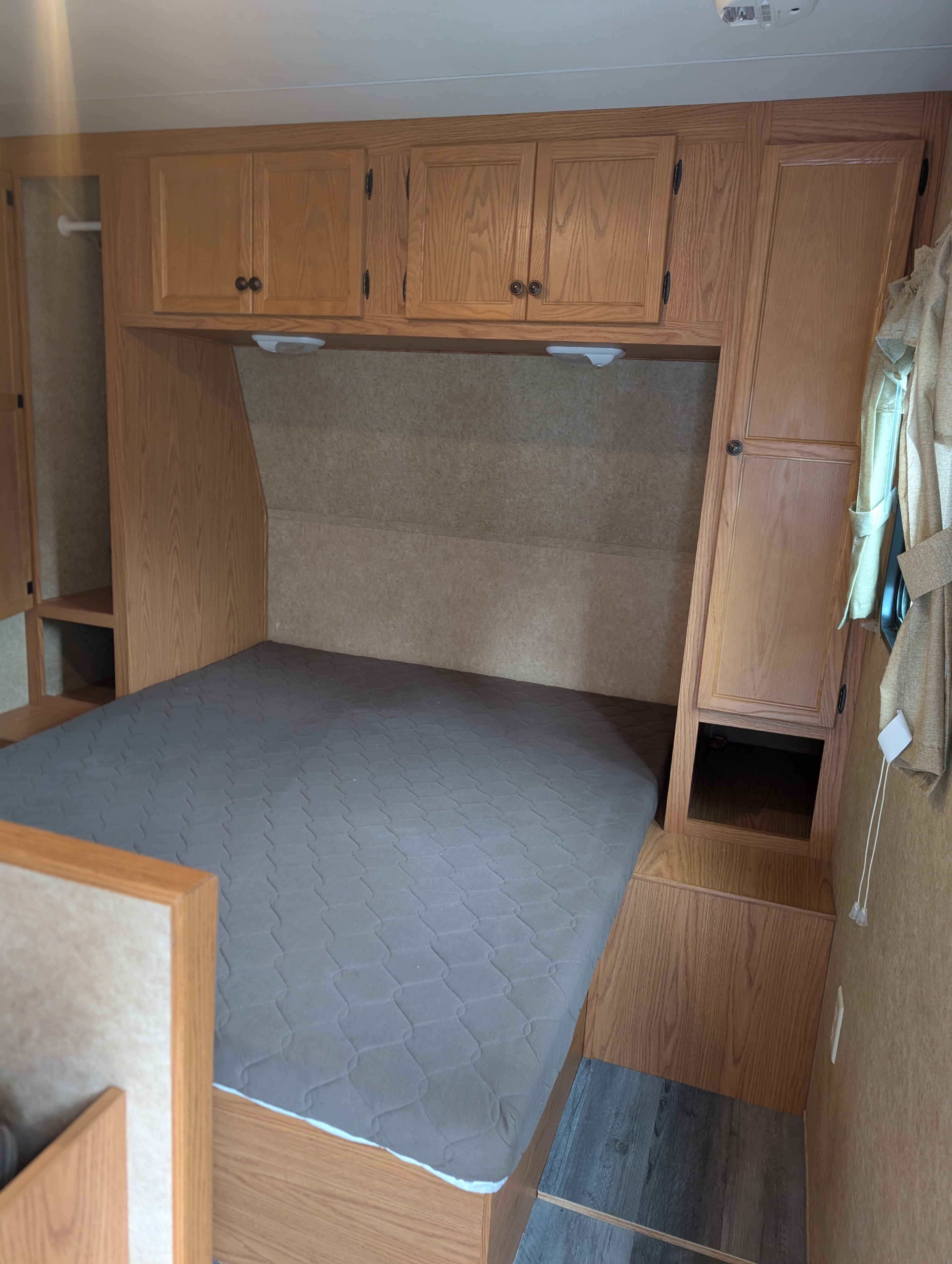RV rental bedroom featuring a comfy bed with overhead cabinets and built-in storage on both sides.. Heartland RVs Trail Runner 2011