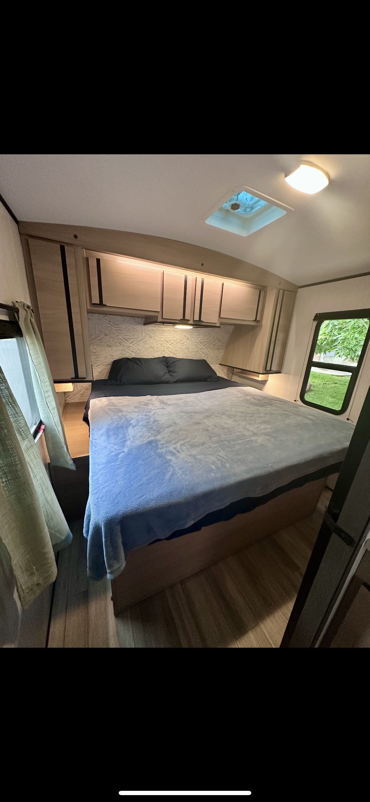 Cozy RV rental bedroom: A comfortable bed, overhead storage, windows, and ceiling vent offer a functional, inviting space.. Cruiser RV Radiance 2022