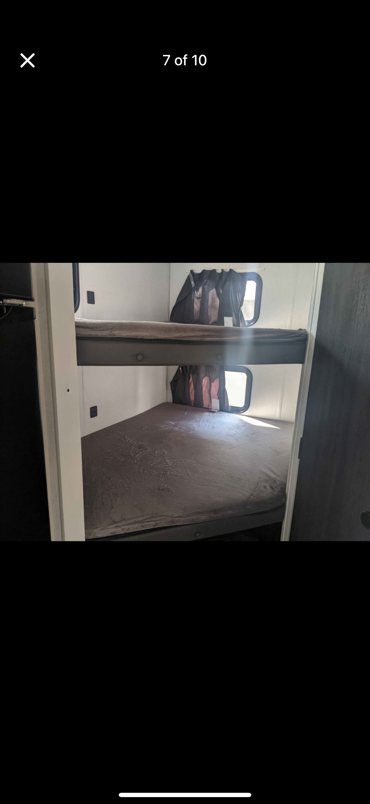 Two bunk beds with dark mattresses and windows inside an RV rental, offering comfortable sleeping.. Forest River Salem FSX PLATINUM 2021