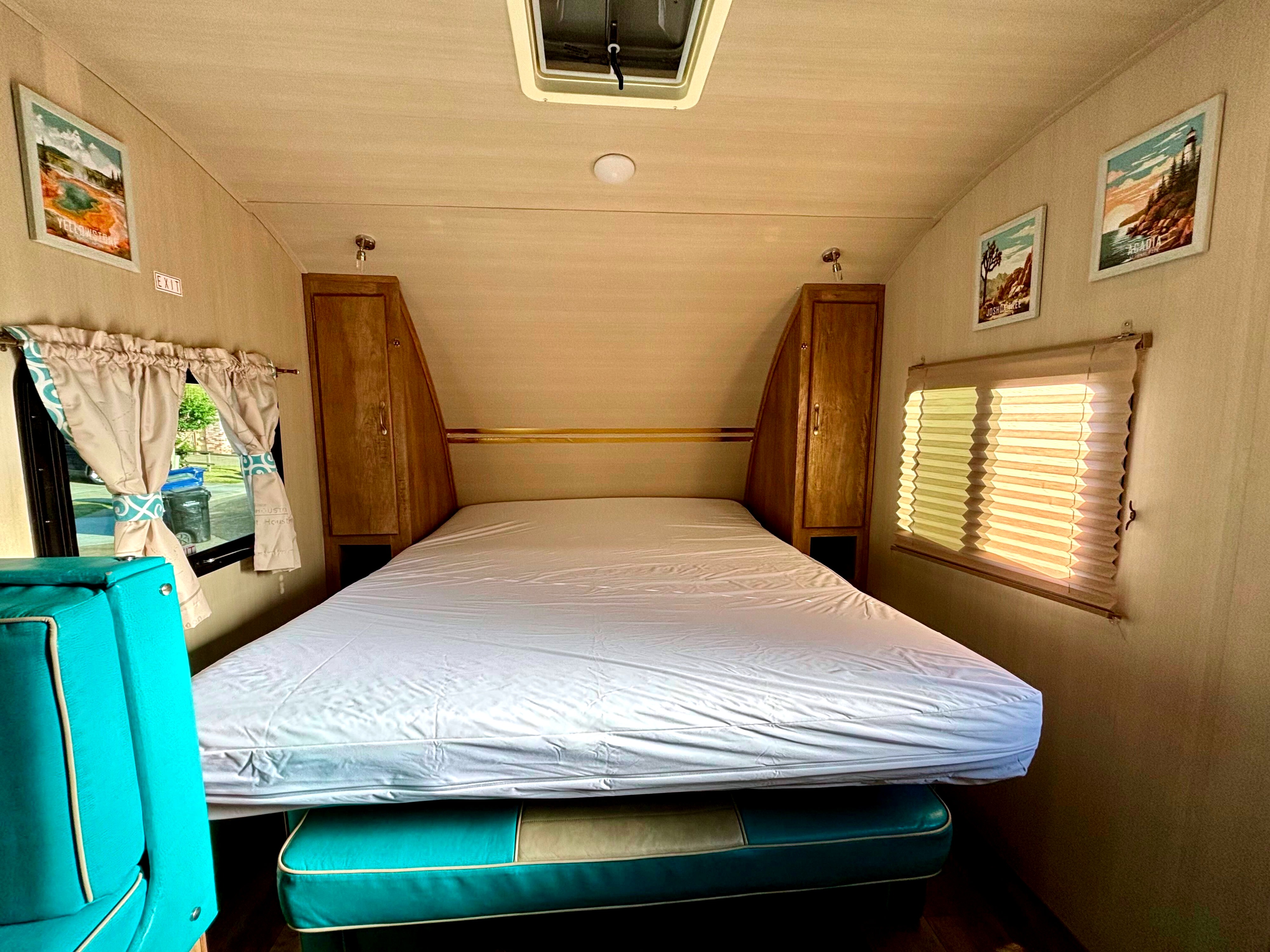 Inside a comfy RV rental: spacious bed flanked by storage, national park art, and bright windows.. Gulf Stream Vintage Cruiser 2021