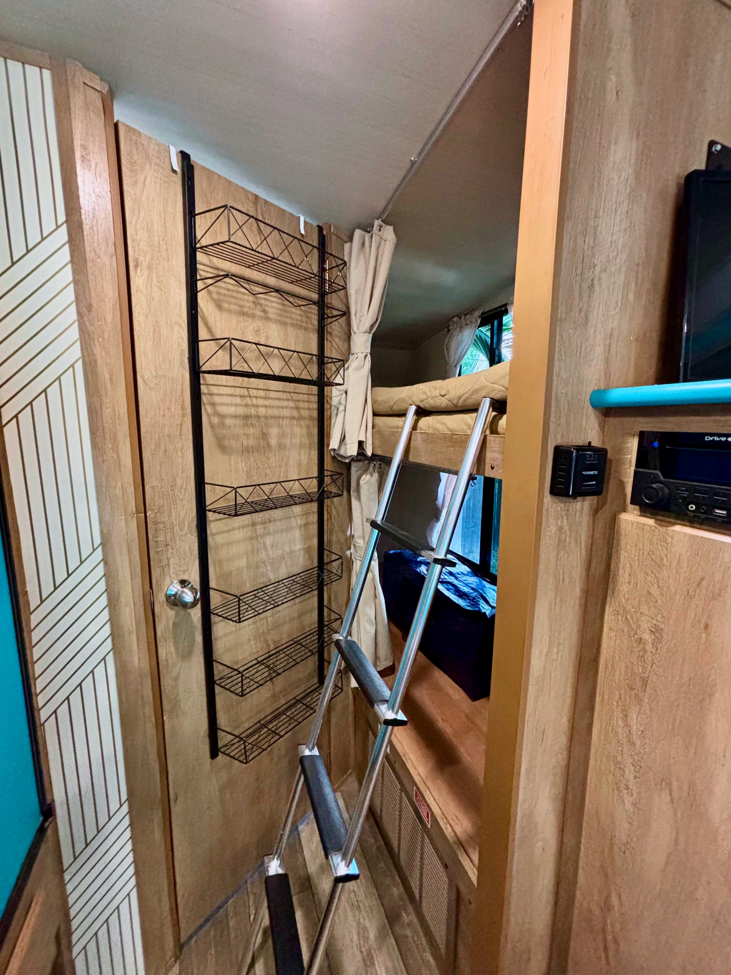 Explore the cozy interior of an RV rental, featuring bunk beds, a ladder, and convenient wall-mounted storage shelves.. Gulf Stream Vintage Cruiser 2021
