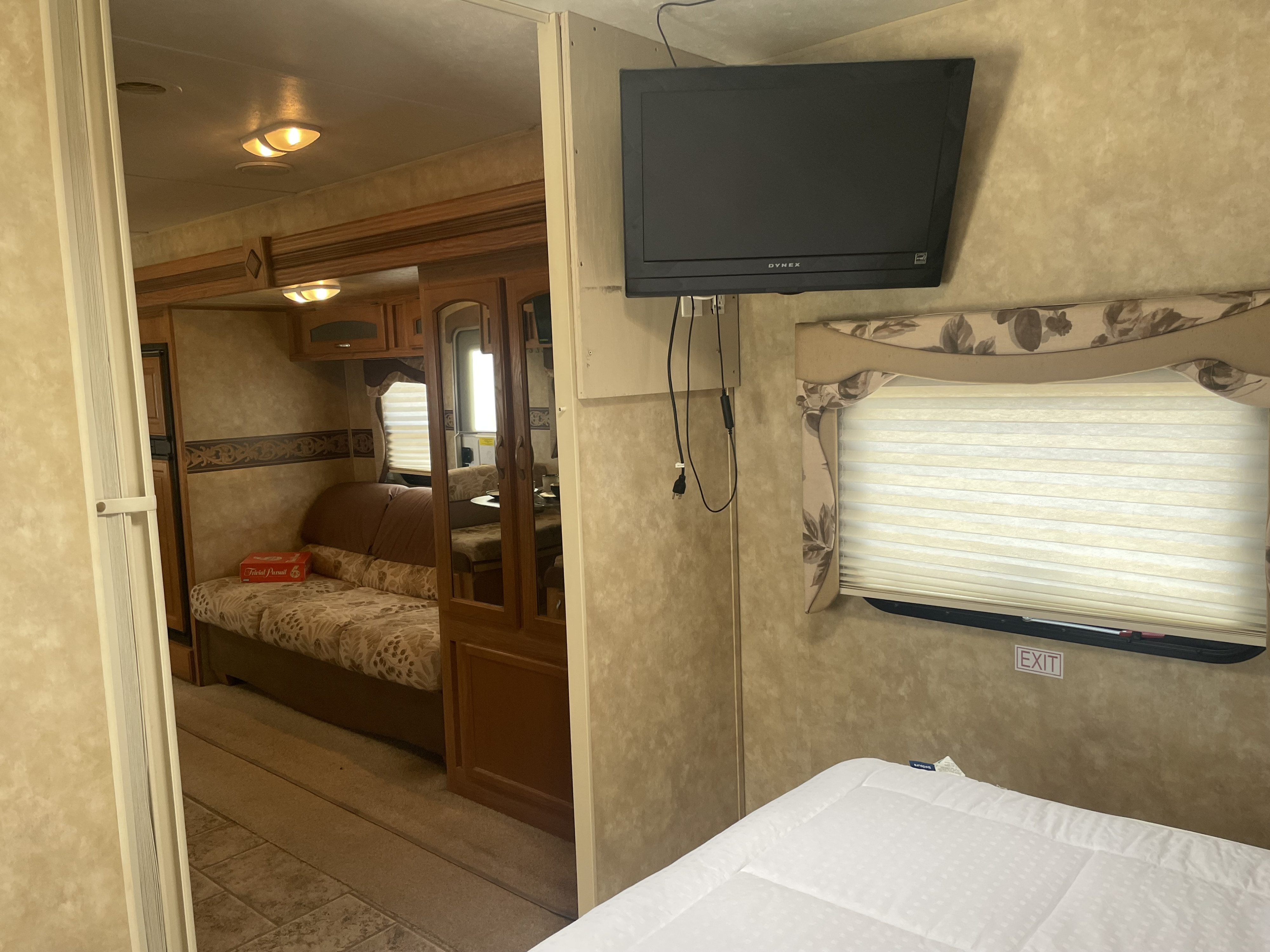 RV rental interior: a bedroom with TV & bed, opens to living area with couch & kitchen. Cozy camper space.. Jayco Eagle Super Lite 2010