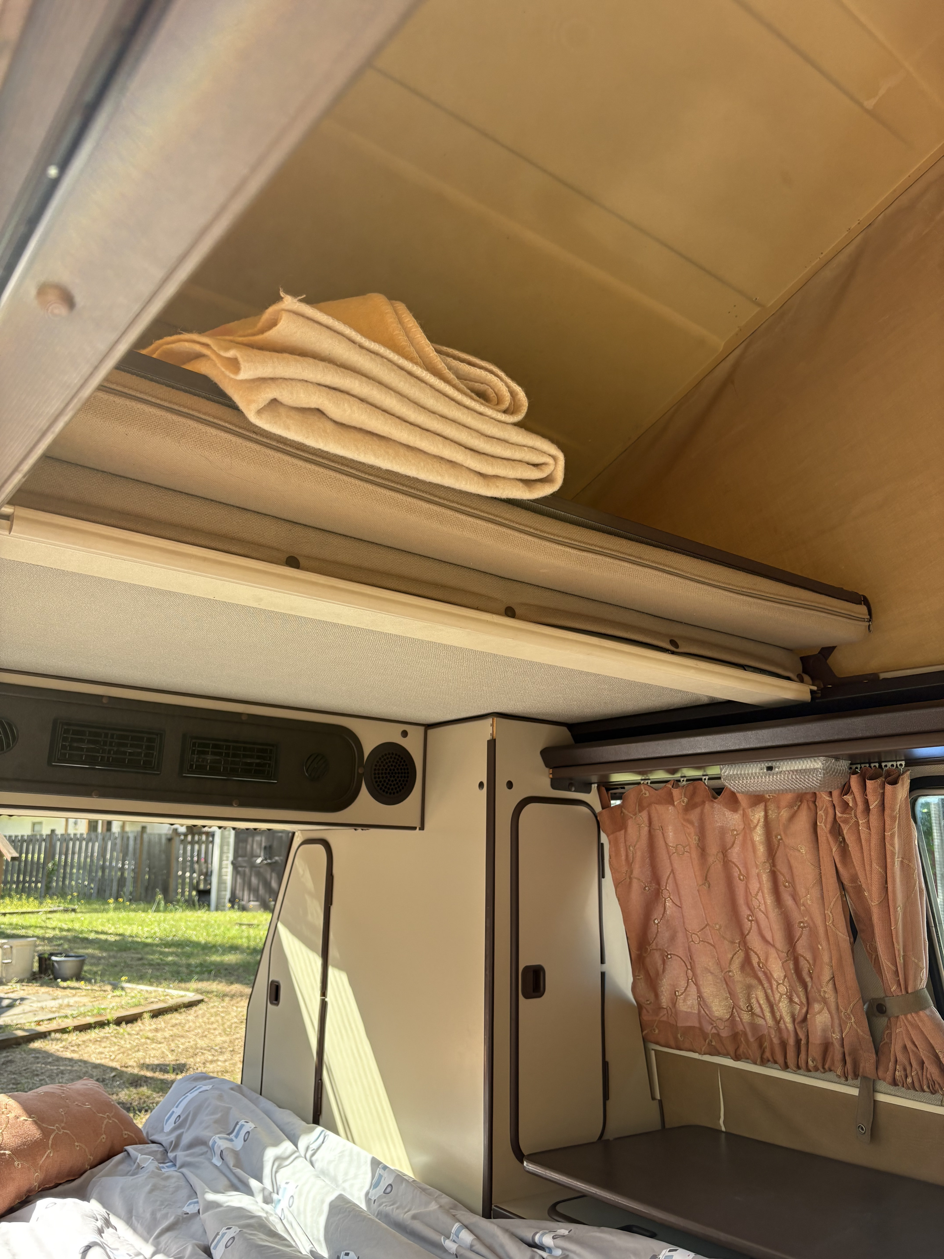 Inside an RV rental: a comfortable sleeping area, overhead storage with blankets, and functional cabinets. Ready for travel.. Westfalia T3 Westfalia 1986