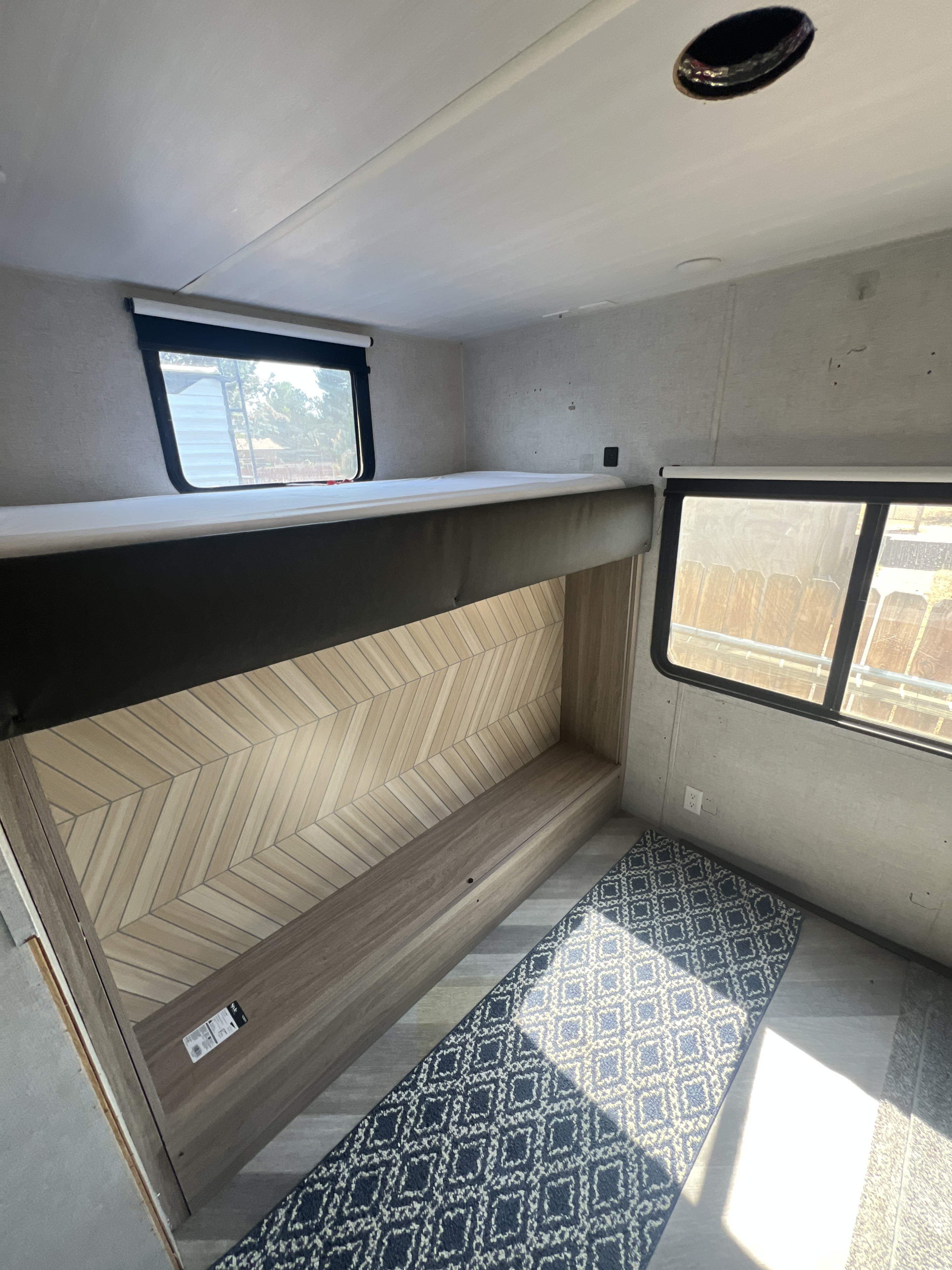 Cozy RV rental interior showcasing built-in bunk beds, a chic chevron wall, and bright windows.. Forest River Wildwood 2020