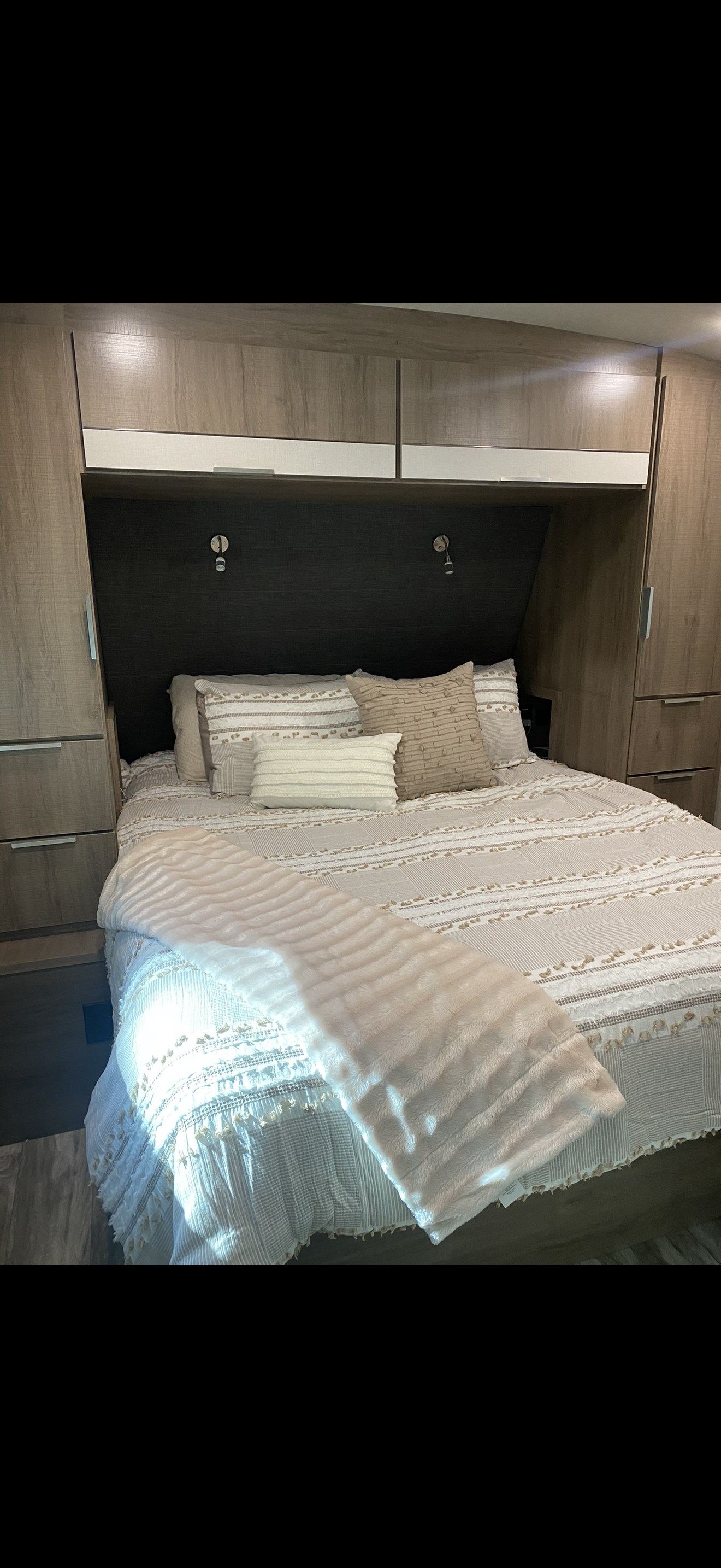This cozy RV rental bedroom features a comfortable bed with neutral bedding and ample storage cabinets, ideal for your trip.. Grand Design Imagine 2021