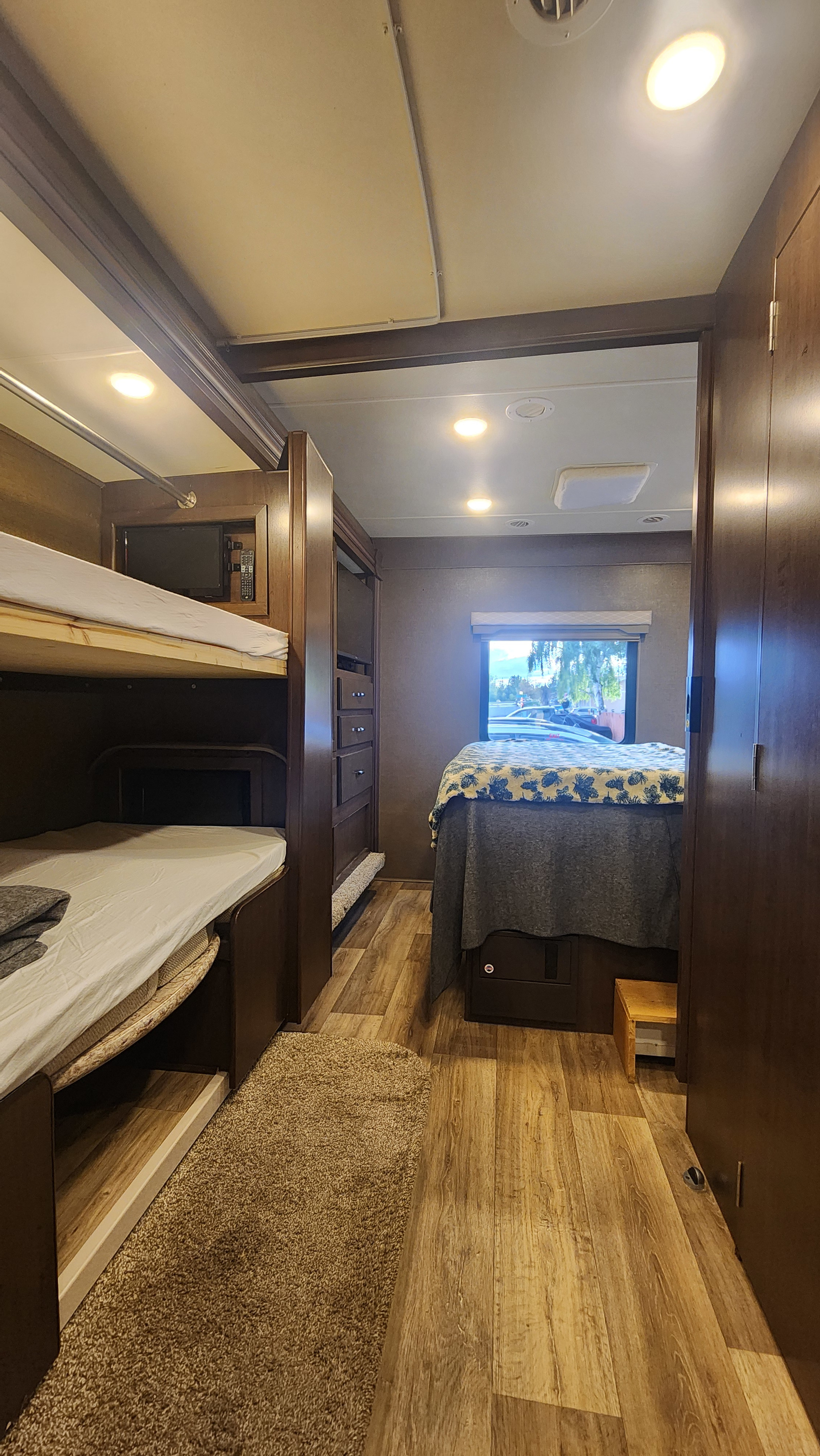 RV rental interior: A cozy bedroom with stacked bunk beds on the left and a master bed with a view on the right.. Thor Freedom Elite 2018