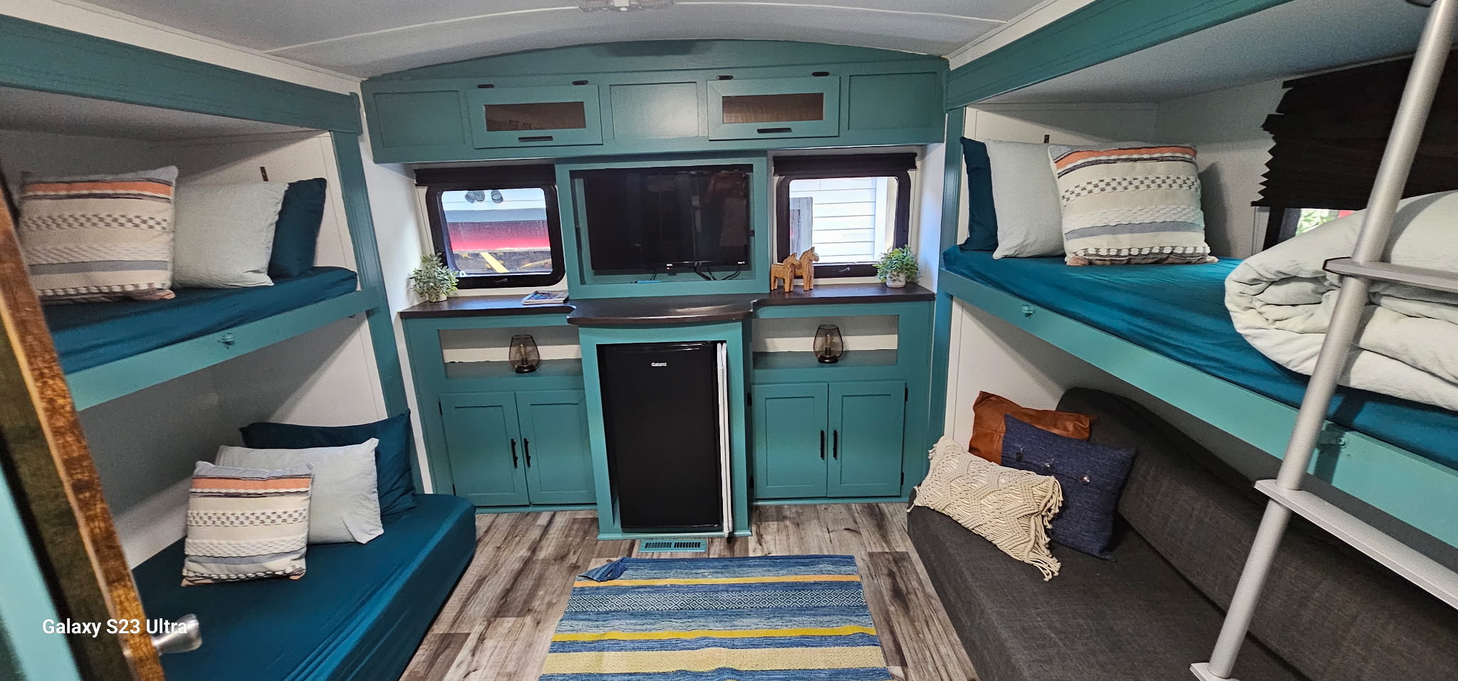 Spacious RV rental interior featuring teal bunk beds, a cozy seating area, and entertainment setup. Perfect for family adventures.. Dutchmen Aerolite 2014