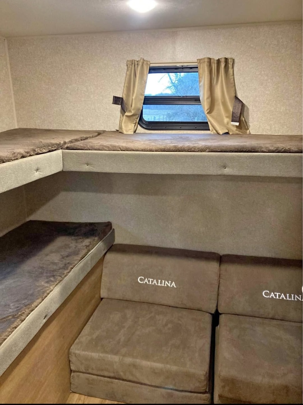 Inside an RV rental: view of comfortable bunk beds, a window with curtains, and flexible seating.. Forest River Coachmen Catalina Legacy 2019