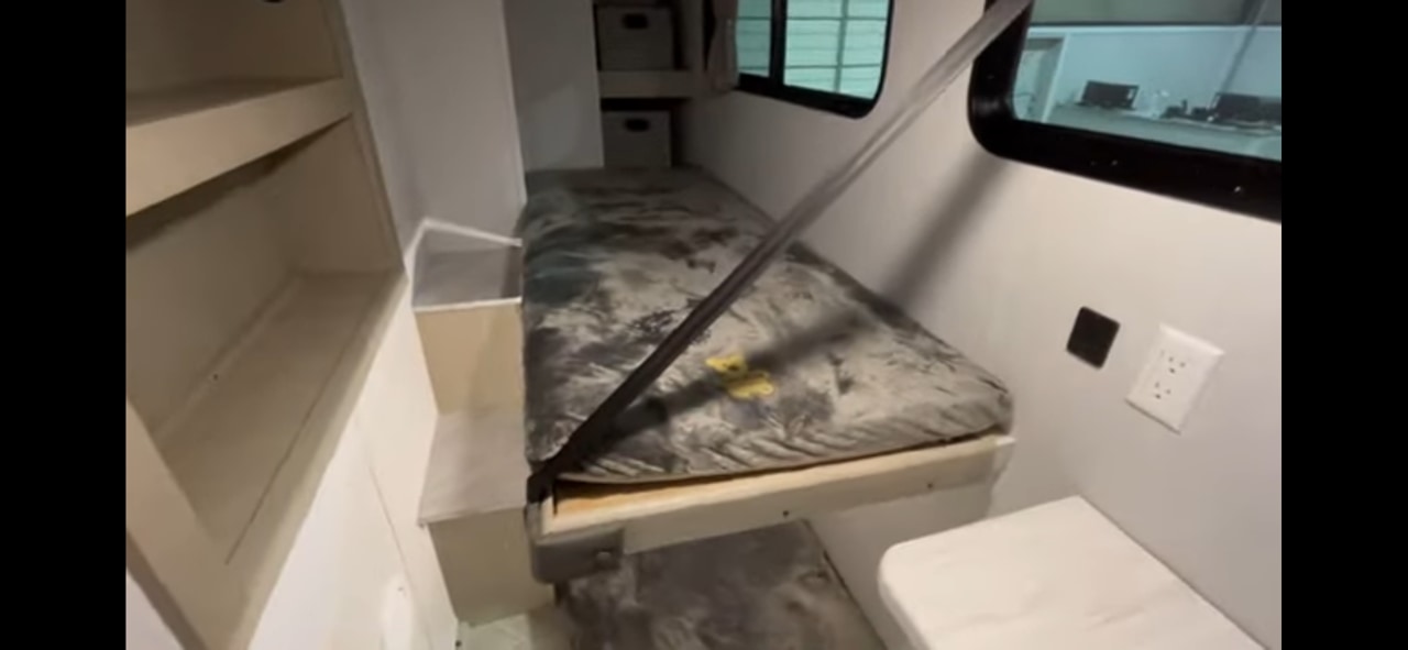 Compact **rv rental** interior: a bunk bed with a strap, shelves, window, and electrical outlet in a cozy space.. Forest River Salem View 2024