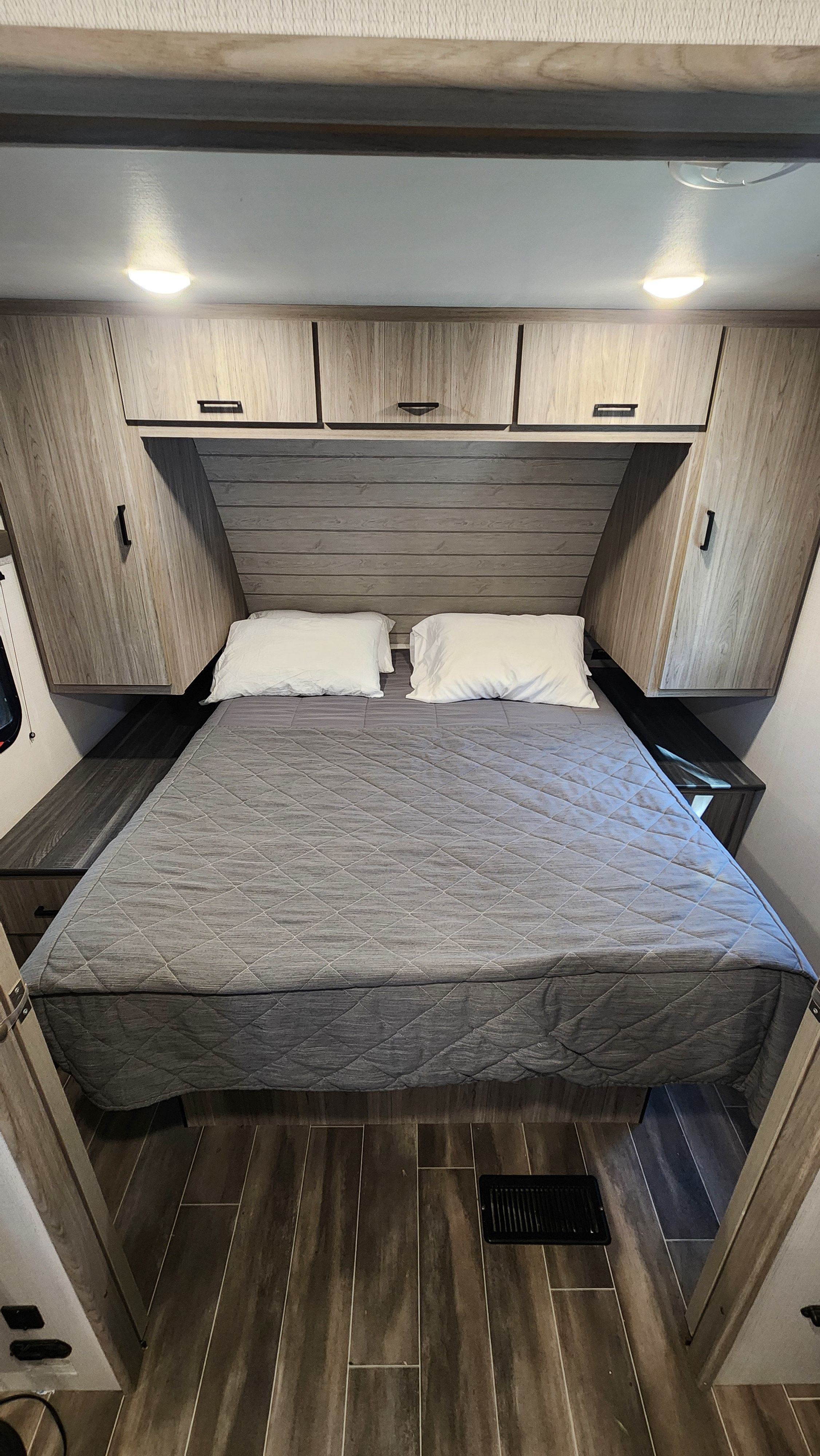 Experience comfort in this RV rental bedroom. Features a cozy bed, ample storage via overhead cabinets, and modern interior design.. Keystone RV Passport SL 2022