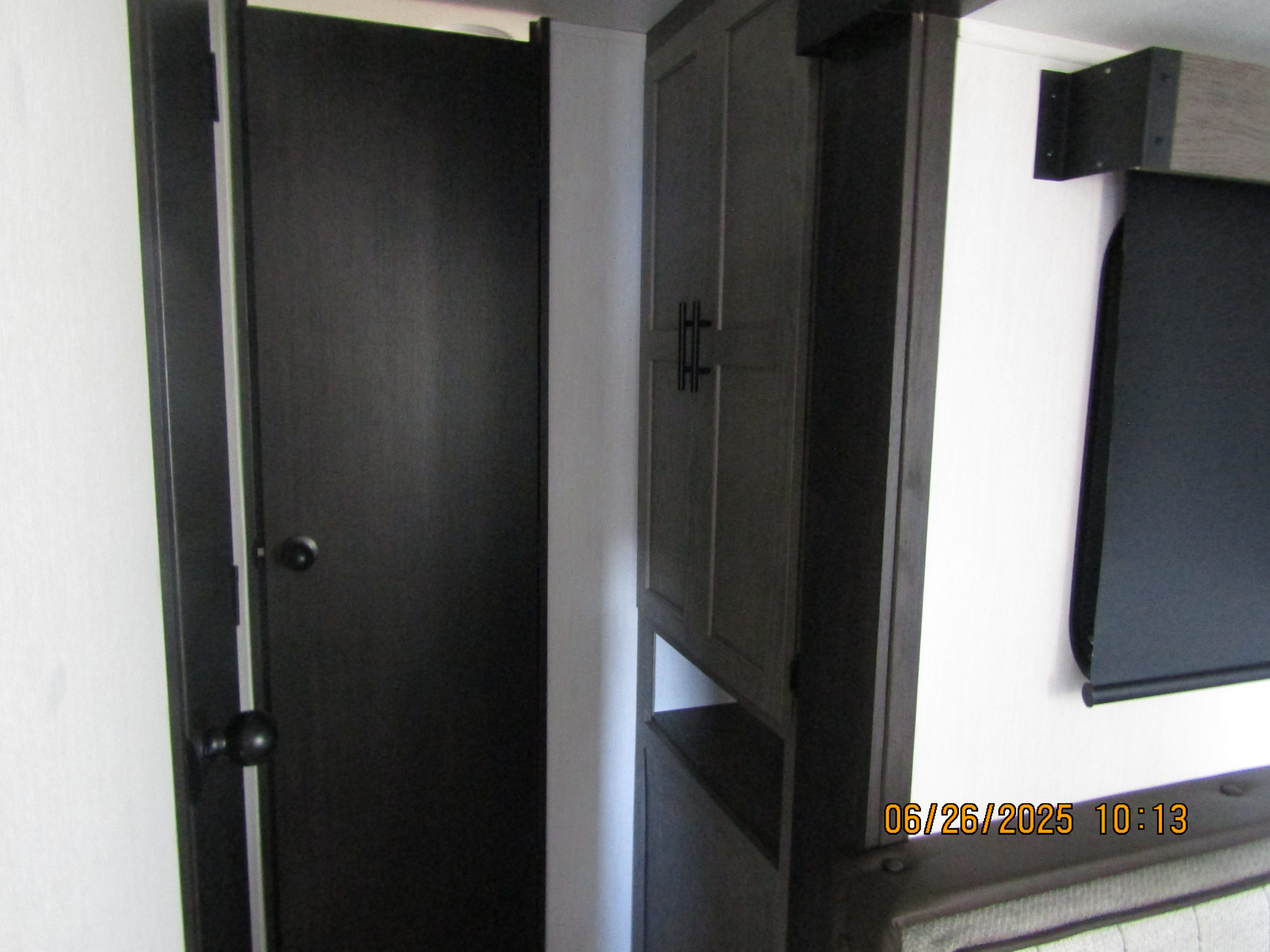 RV rental interior showcasing dark wood cabinetry, a door, open storage, and a partial view of upholstered seating.. Forest River Inc. Alpha Wolf 2026