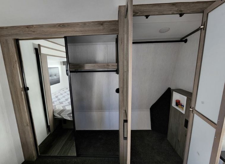Efficient RV rental bedroom & wardrobe with mirrored sliding doors and a dedicated laundry area for compact living.. Heartland RVs Elkridge 2022
