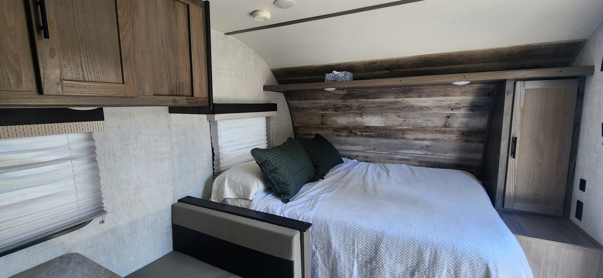 RV rental bedroom: a cozy space with rustic wood paneling, a full bed, and convenient overhead storage.. Gulf Stream Enlighten 2021