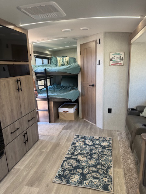 RV rental interior featuring cozy bunk beds, a living area, and modern wood finishes. Perfect for your next trip!. Grand Design Imagine 2024