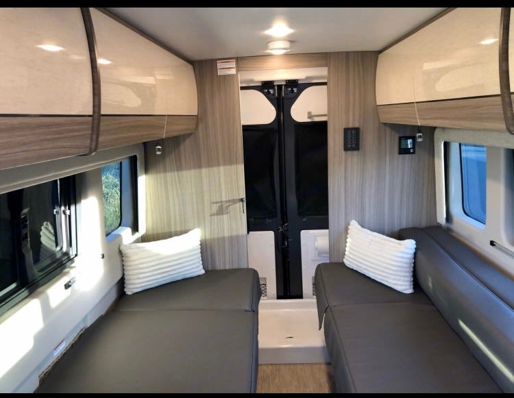 RV rental: Inside a modern camper van with dual beds, overhead cabinets, and bright windows.. Jayco Swift 2021