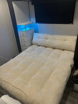 Cozy RV rental bedroom with a comfy padded bed, blue LED lighting on storage, and a dark window blind.. Jayco Jay Flight SLX 2024