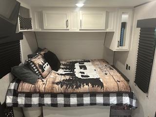Cozy RV rental bedroom with queen bed, overhead cabinets, and windows. Perfect for travel accommodations.. Jayco Jay Flight SLX 2024