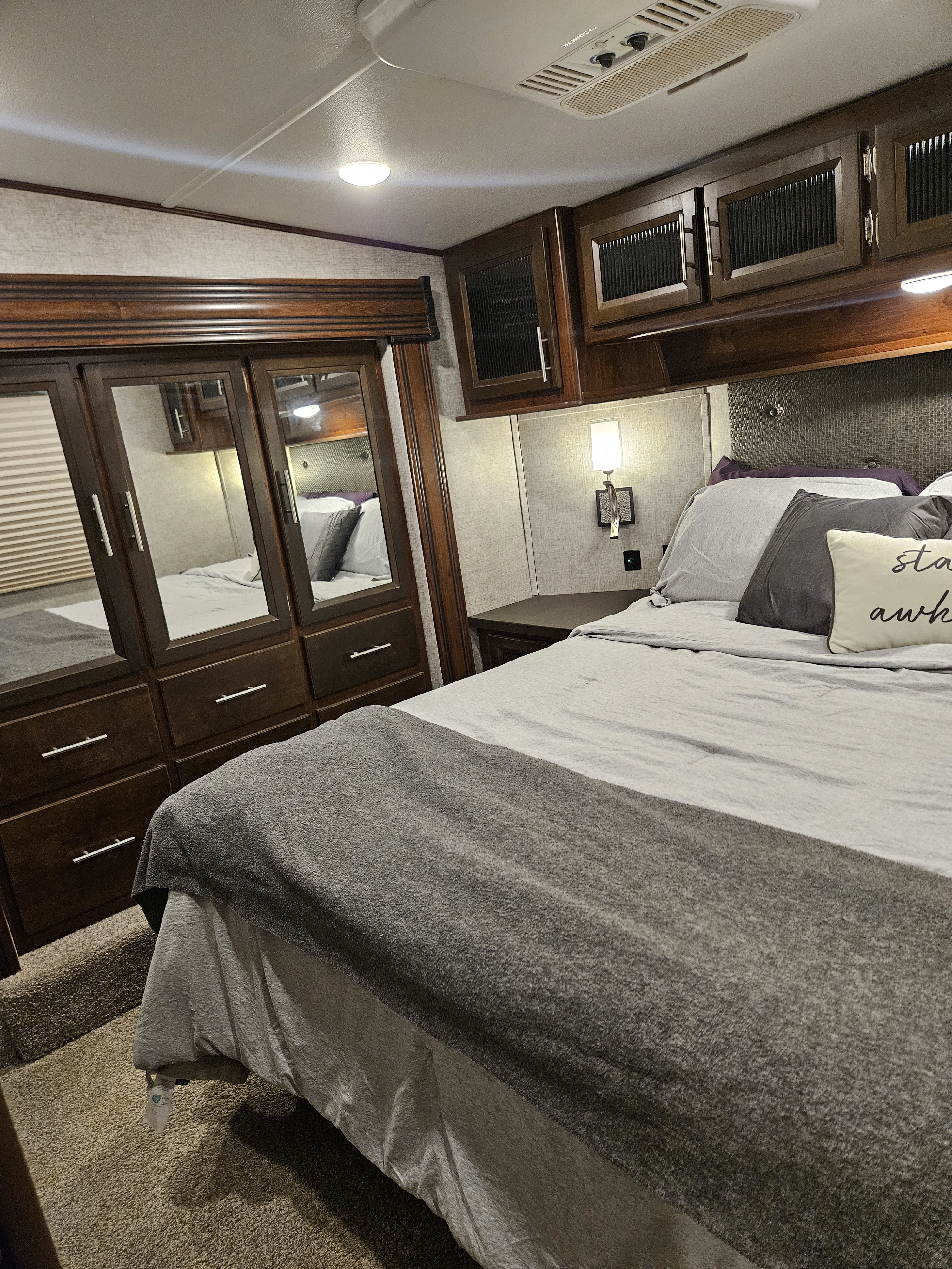 Experience comfort in this RV rental bedroom featuring a cozy bed, dark wood cabinets, and mirrored wardrobe.. Forest River Vengeance 2019