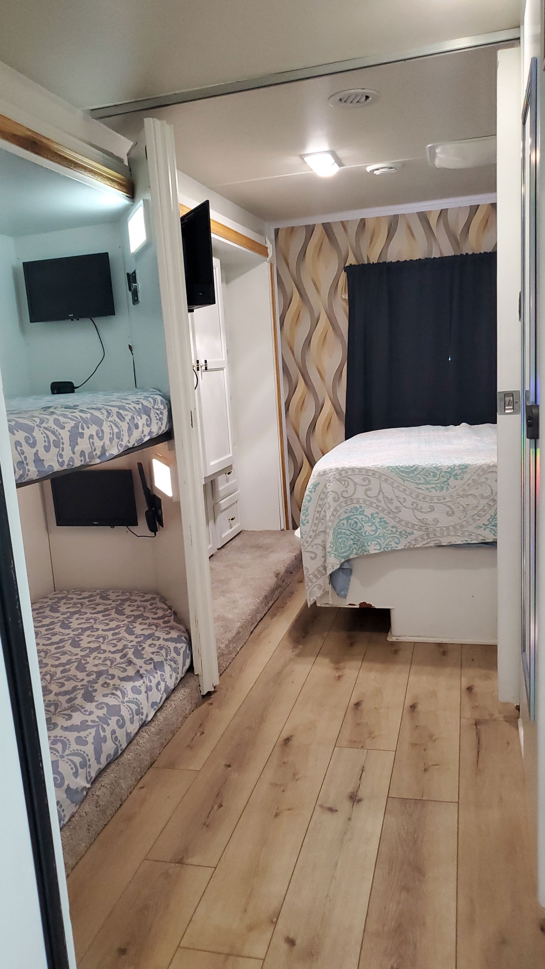 RV rental interior: bunk beds with TVs on the left, a master bed on the right, and modern styling.. CoachMen Freelander 2012