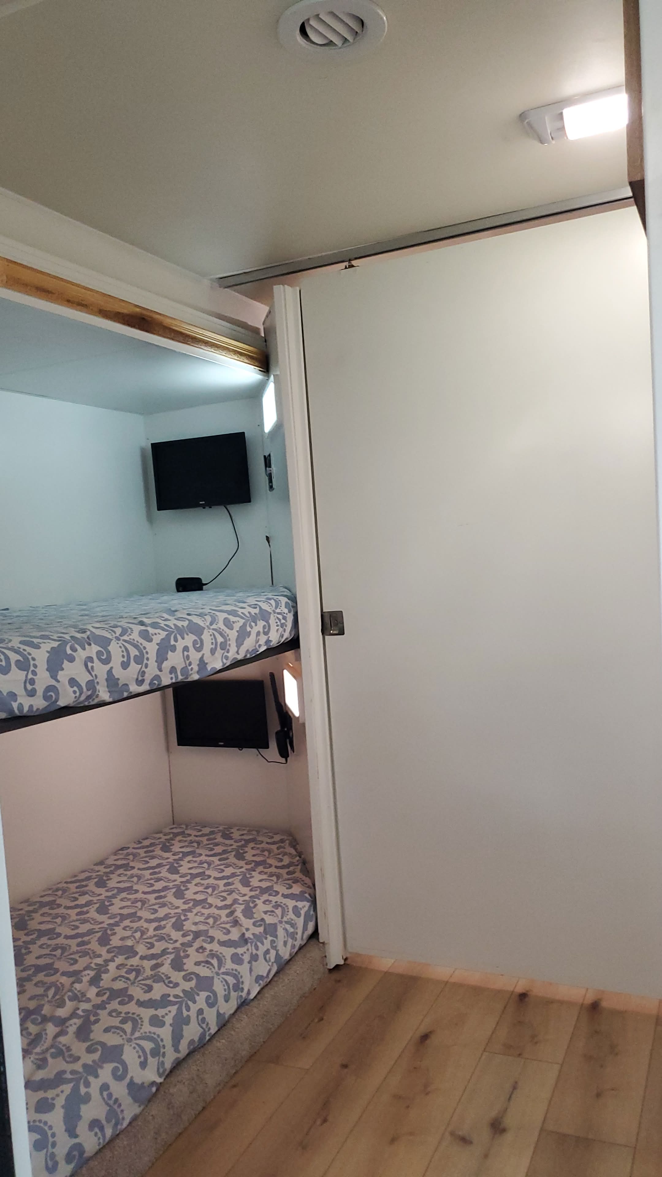 View of a compact RV rental sleeping area featuring two bunk beds, each equipped with a TV for guest comfort.. CoachMen Freelander 2012