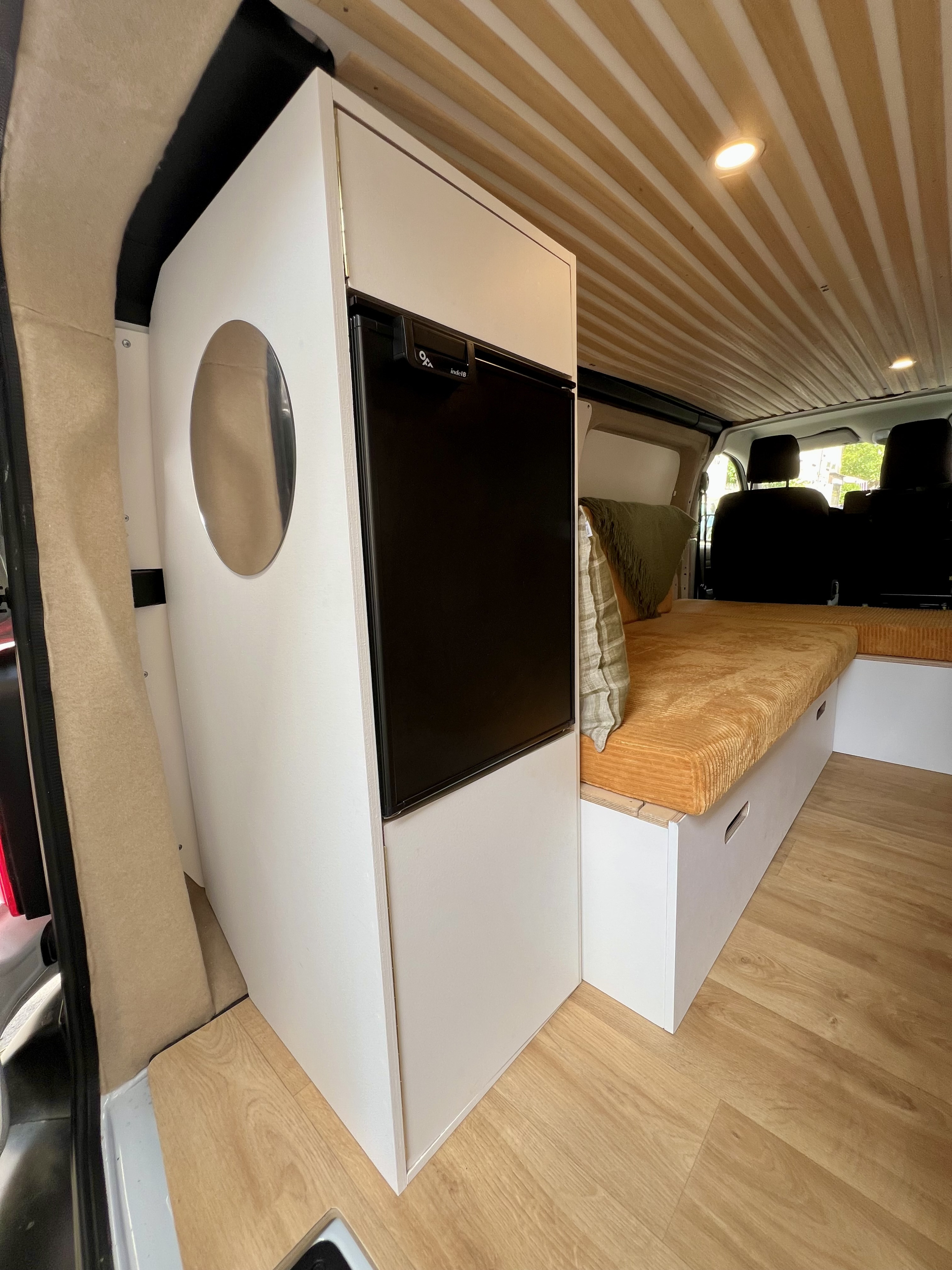 Explore this RV rental's clever interior: compact fridge, cozy bed with storage, and stylish wood-slat ceiling.. Renault Trafic 2024