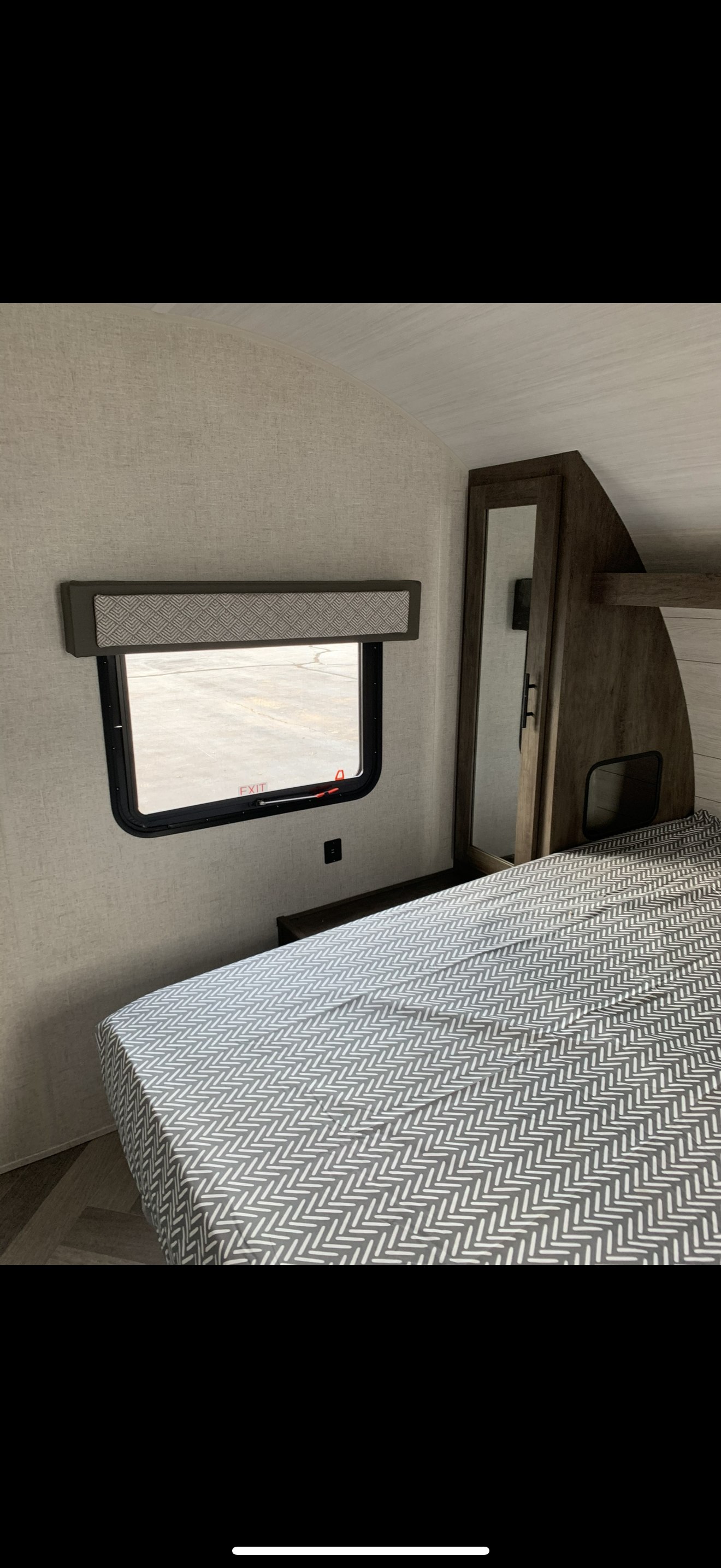 RV rental interior featuring a cozy bedroom with patterned bedspread, window, and storage for comfortable stays.. Forest River Salem Cruise Lite 2021