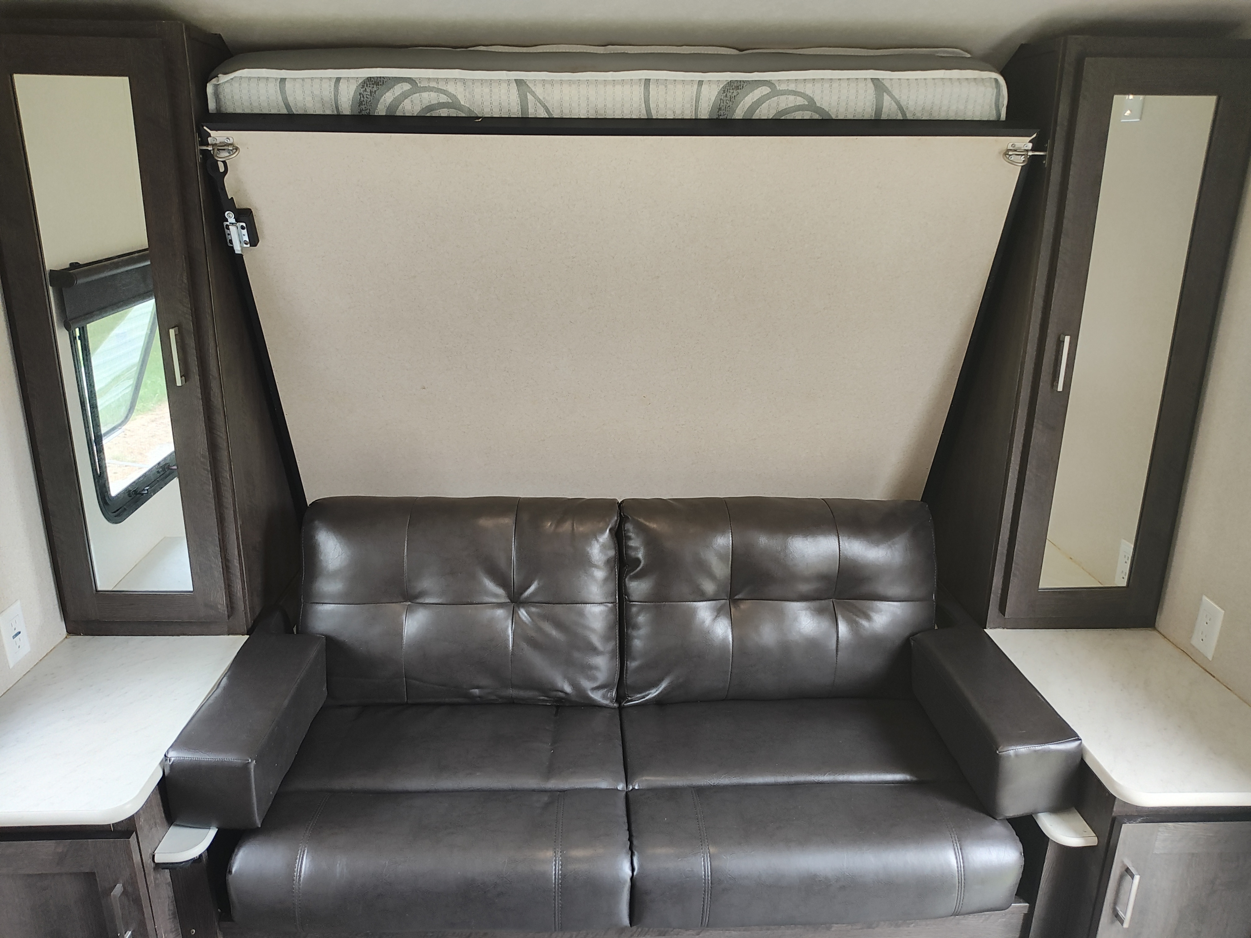 RV rental interior: Dark leather sofa with built-in storage. Features a hidden Murphy bed with mattress above.. Forest River Salem Cruise Lite 2018