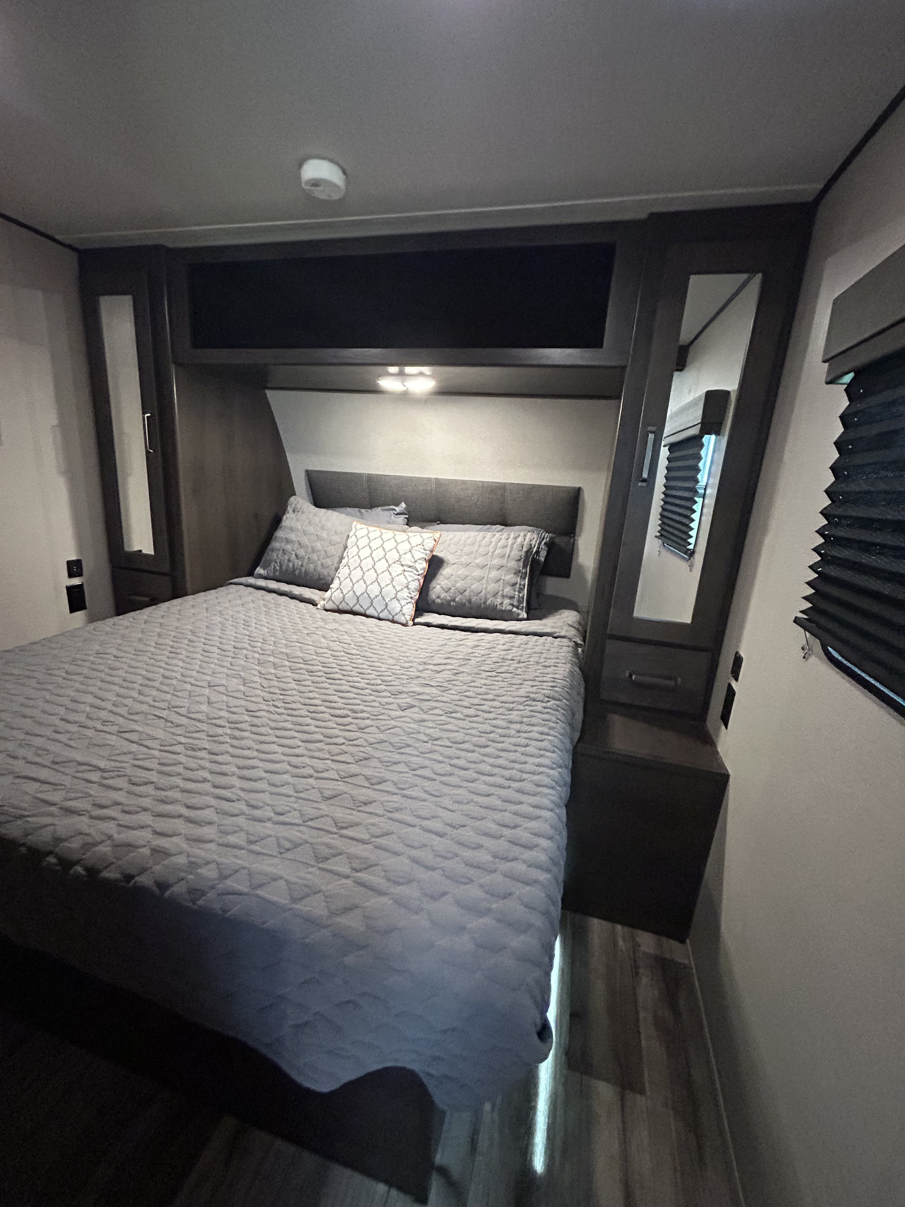 RV rental bedroom with a comfortable bed, built-in storage, and a smoke detector on the ceiling.. Grand Design Transcend Xplor 2022