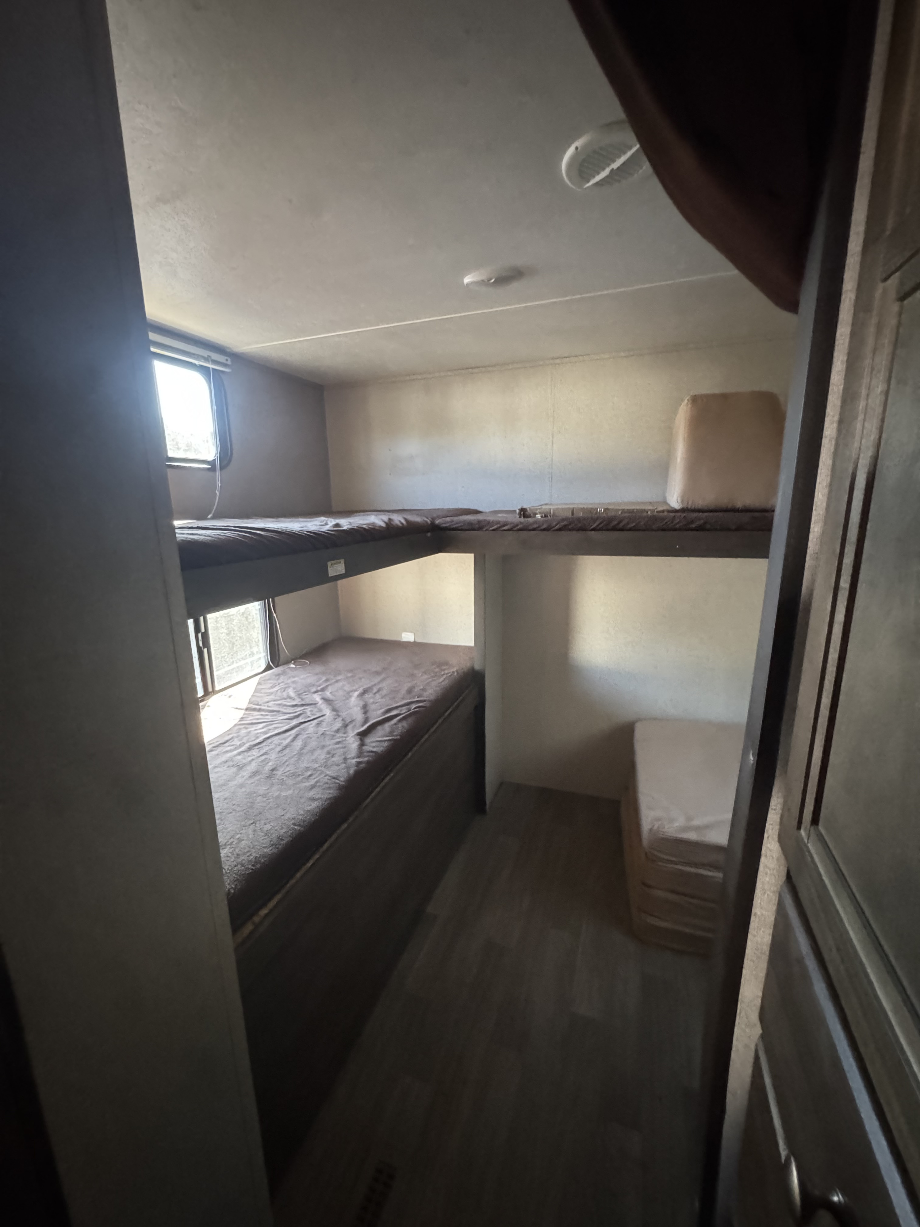 RV rental bunkhouse: A view of the two bunk beds, one with an L-shaped extension, and extra floor space with a mattress.. Dutchmen Coleman Lantern 2018