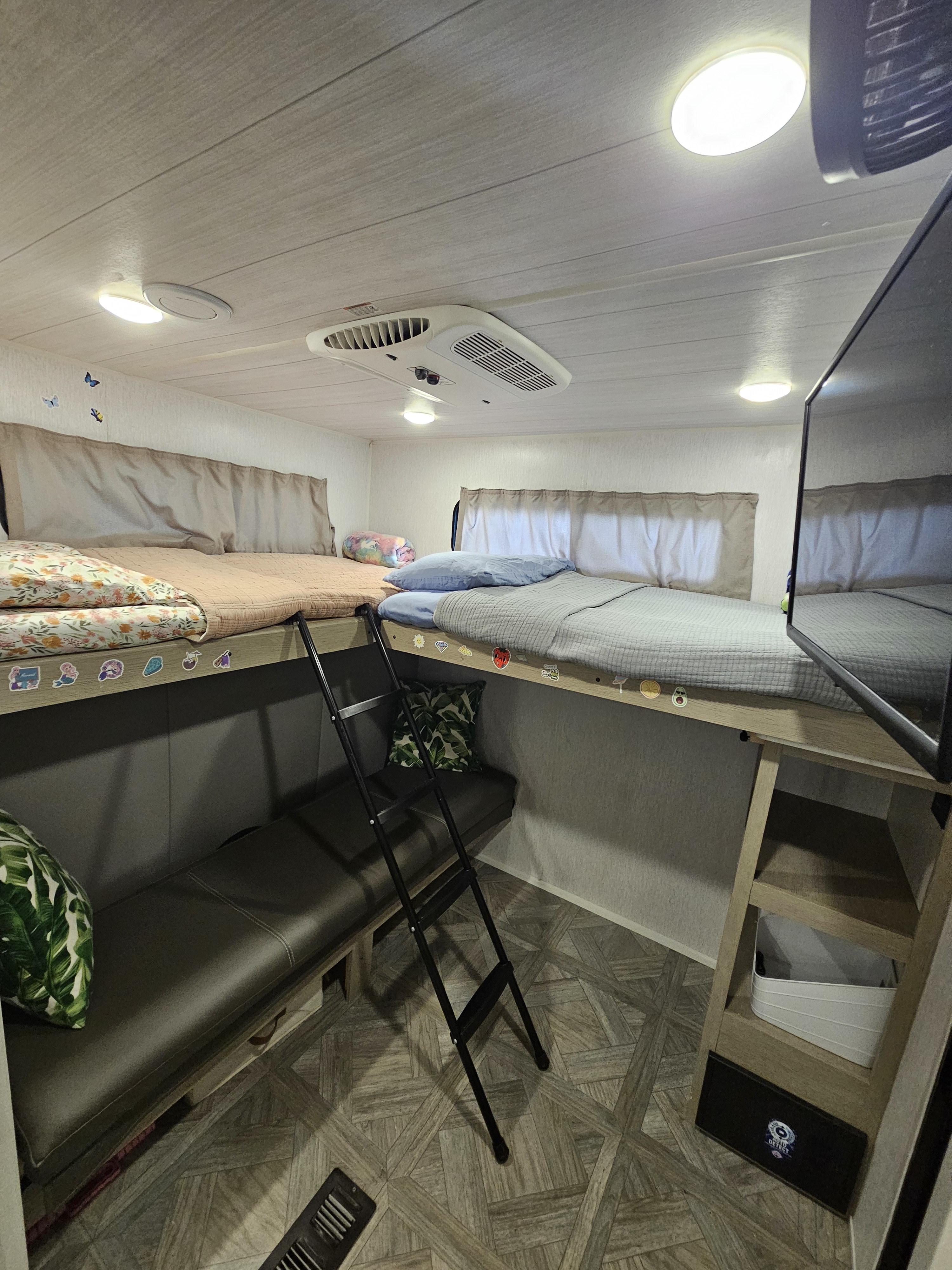 Inside an RV rental: a comfortable bunk bed area with two bunks, a ladder, bench, TV, and AC unit.. Forest River Salem Platinum Model 29VBUD 2023