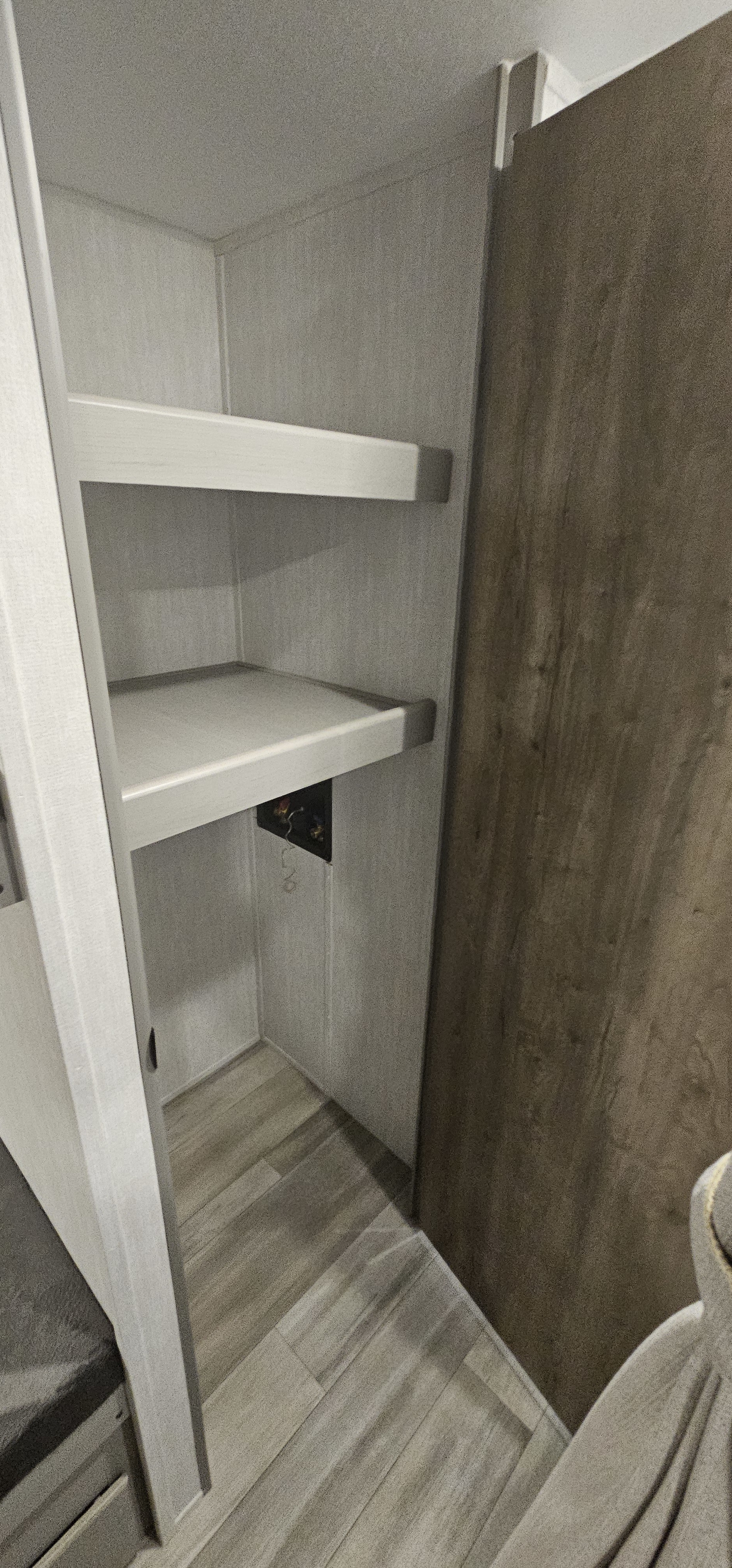 RV rental: Bright, modern storage closet with two white shelves, light walls, wood-look floor, and a small utility panel.. forest river Viking 2025
