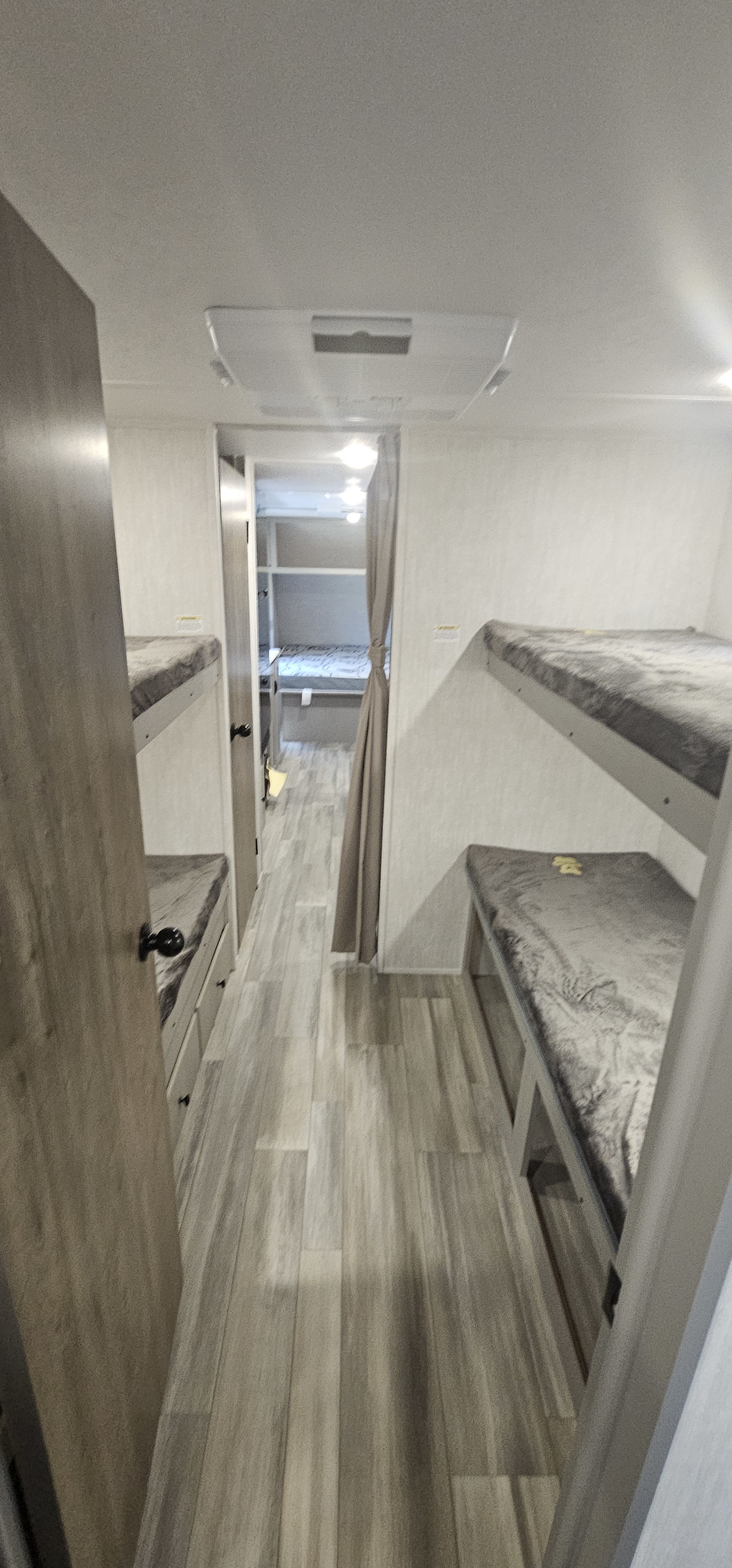 RV rental bunk room: rows of cozy bunks line the hallway, with additional sleeping space through a draped doorway. Light wood flooring.. forest river Viking 2025