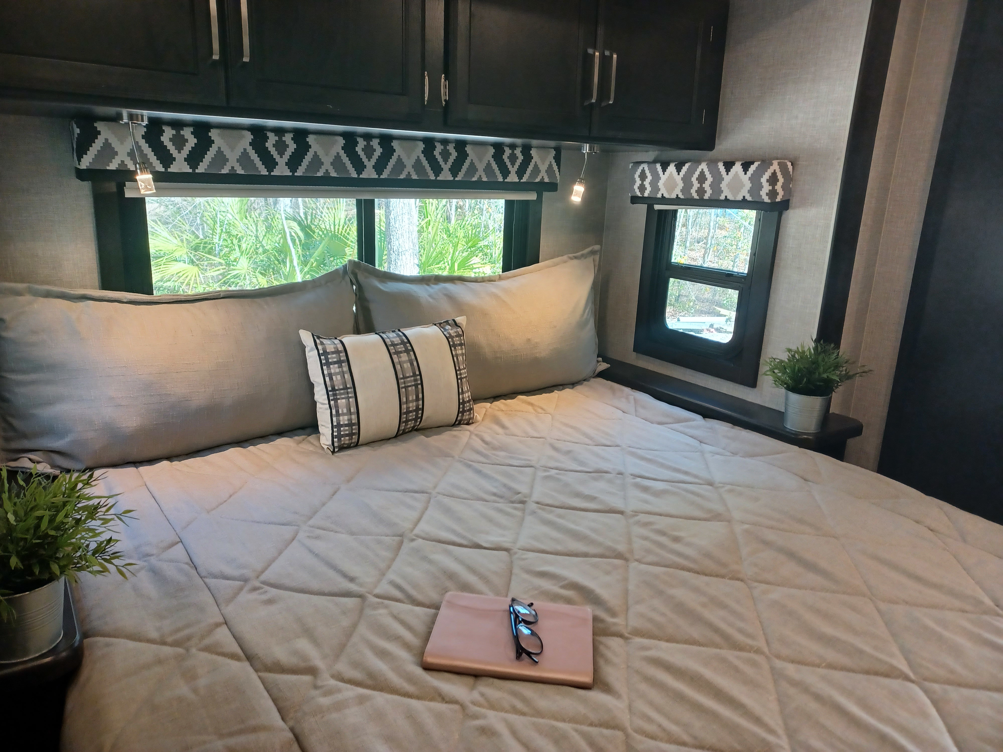 Relax in this cozy RV rental bedroom. Features a comfy bed, outdoor views, overhead storage, and reading lights.. Entegra Coach Vision 2022